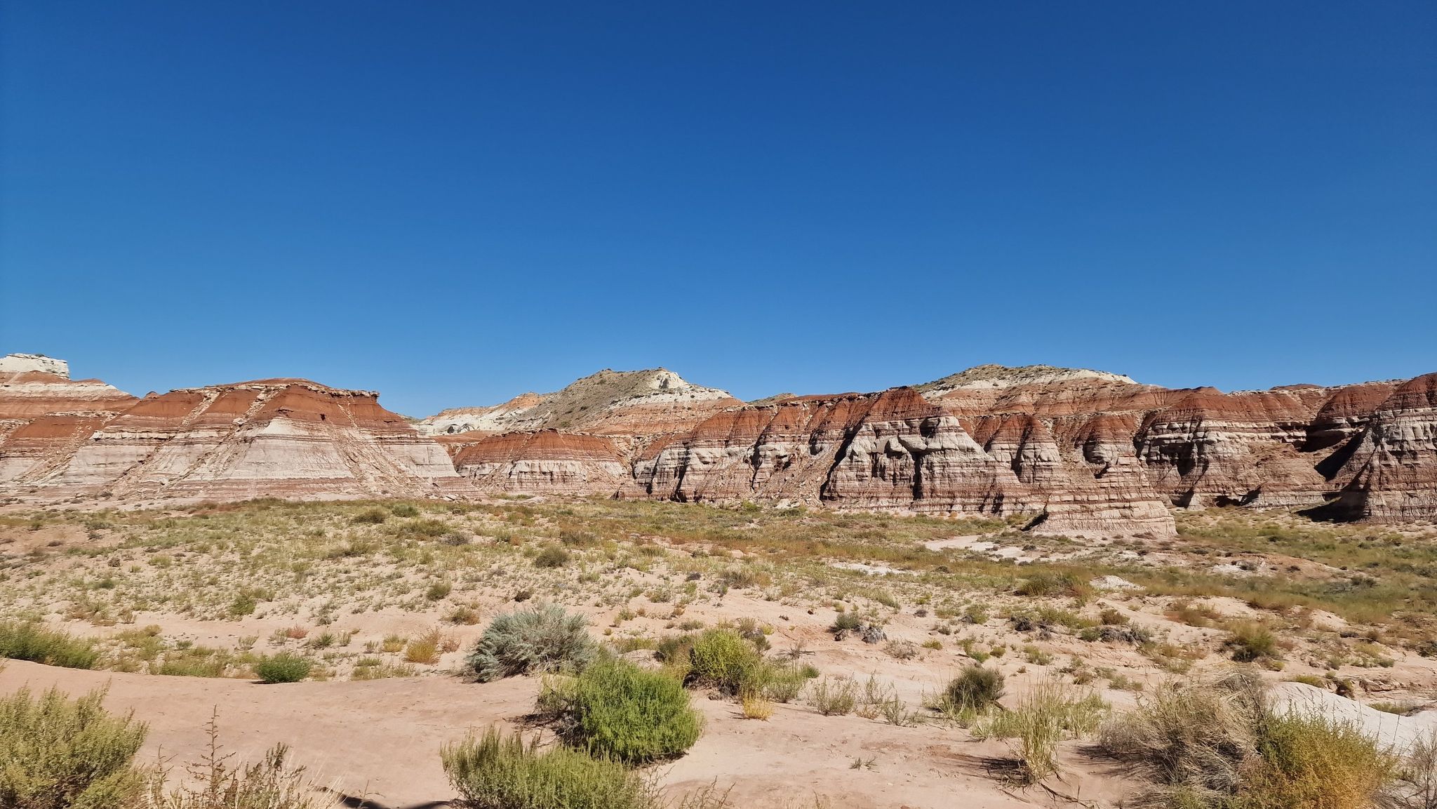 Wide view of layered red and white desert cliffs under a clear blue sky. - Rock Formation loop from Toadstool Hoodoos Parking