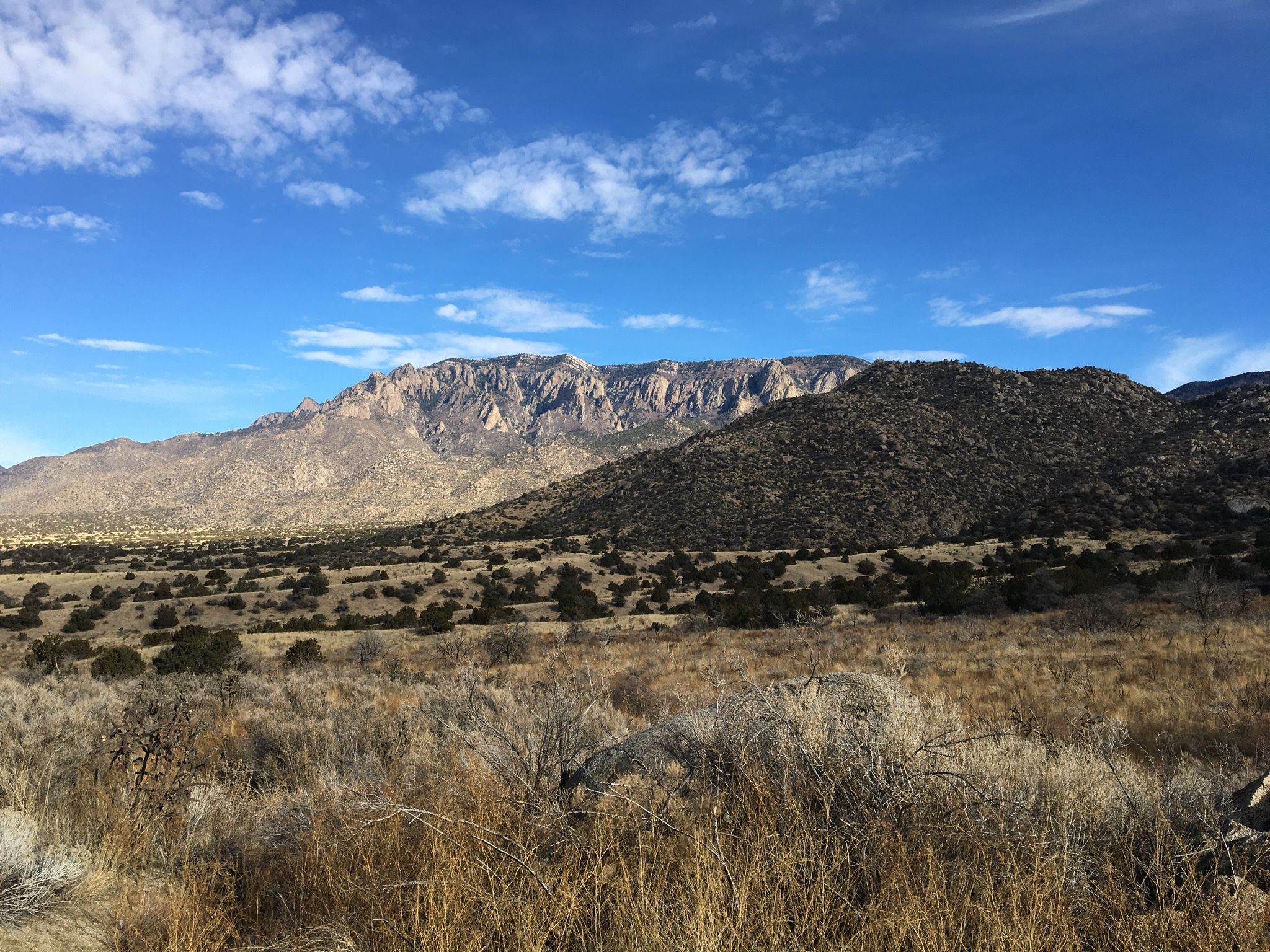 Rugged mountains loom over a dry, brushy landscape under a blue sky. - Michael M Emery Primitive and Trail 305A Loop