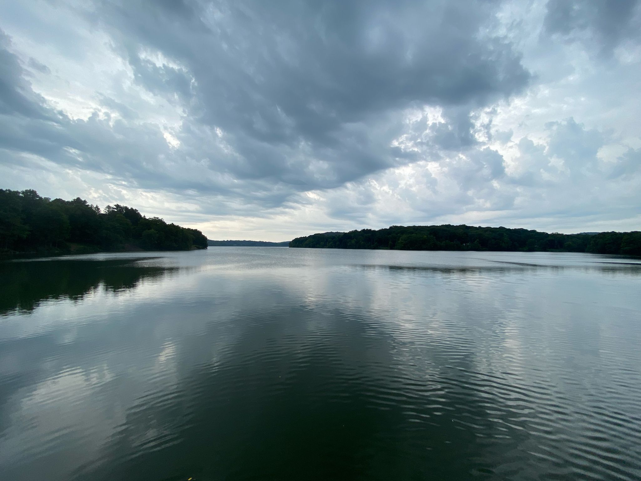 A wide, dark lake reflects a dramatic, cloudy sky at dusk. - Quiet resting spot – Fantastic descent loop from Cold Spring