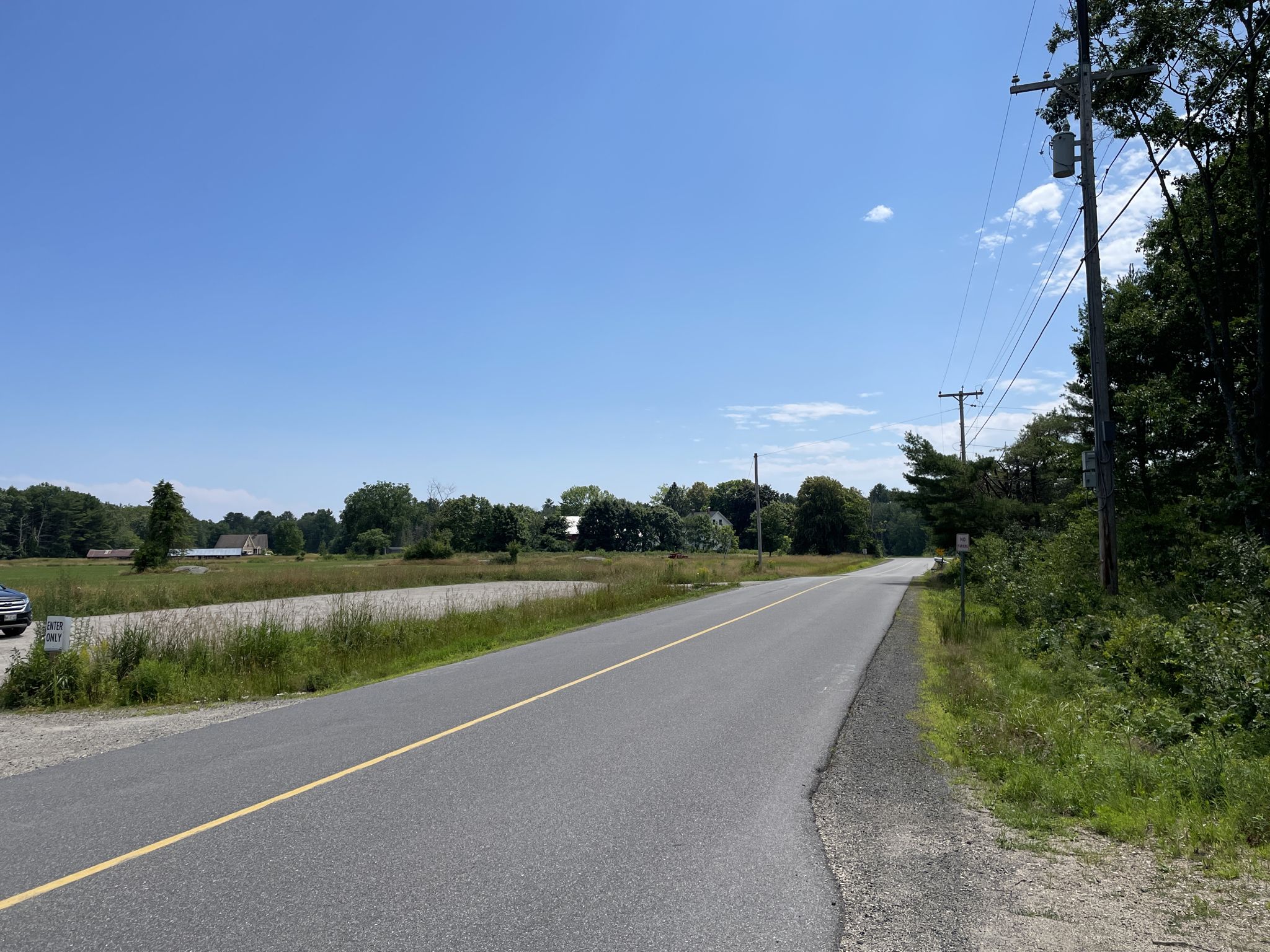 Empty paved road with utility poles under a clear blue sky. - Alewive Woods Preserve – Pepperell Mill Campus loop from Saco