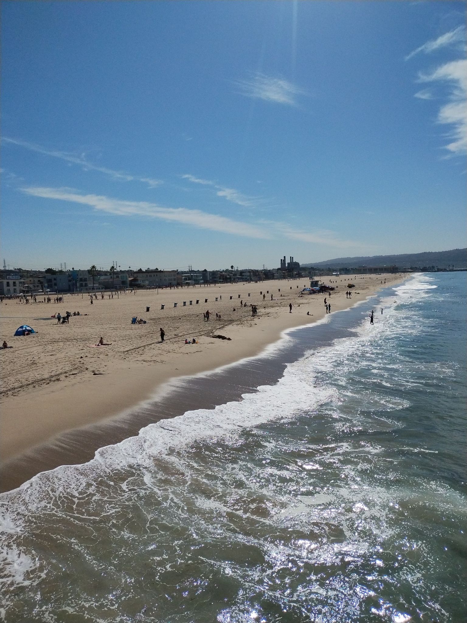Sunny beach with ocean waves, distant buildings, and people enjoying the sand. - Redondo Beach loop from Hermosa Beach