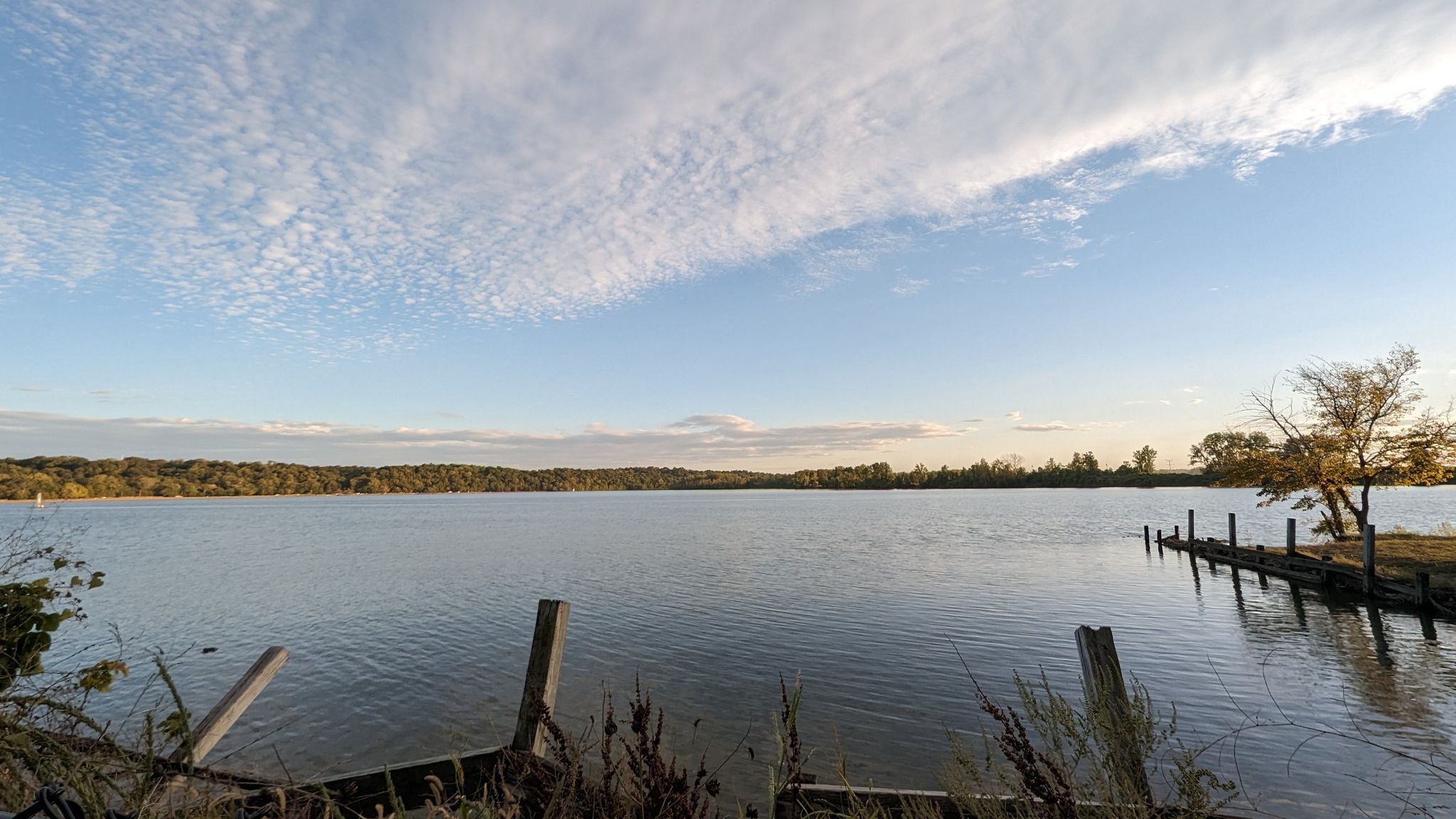 Wide lake with old wooden docks under a partly cloudy, bright sky. - Frontier Park loop from Boat House
