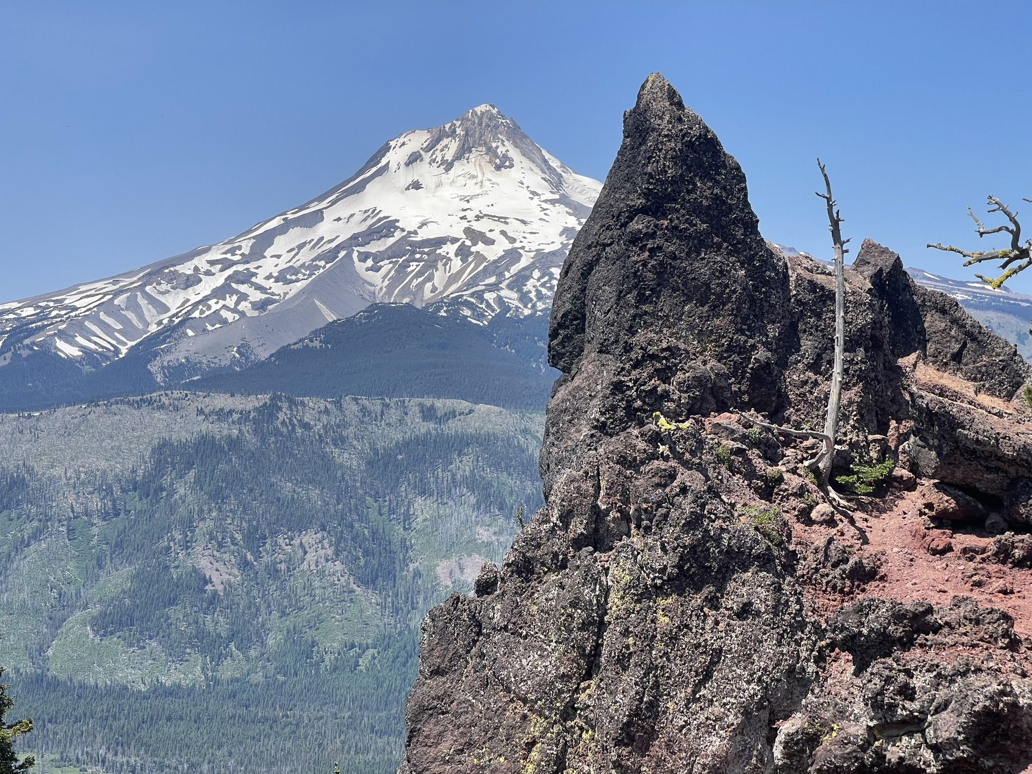 Jagged rock formation in foreground with a snow-capped mountain behind it. - View of Mount Hood loop from High Prairie Trailhead