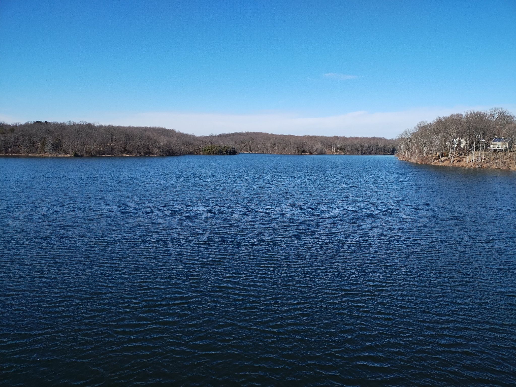 A wide, calm lake surrounded by bare winter trees under a clear blue sky. - Little Seneca Lake – Osprey Heights loop from Boyds