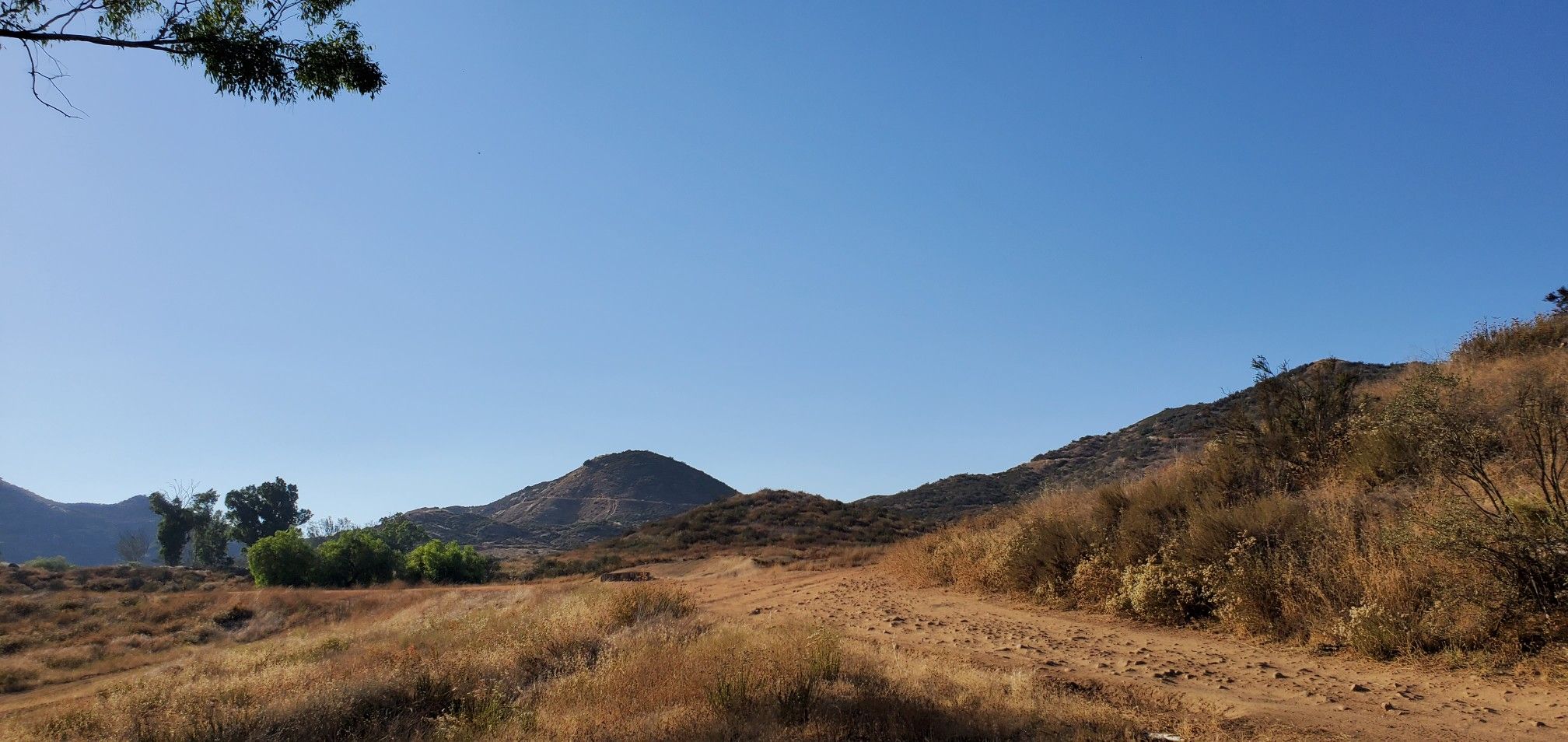 Sunny, dry hilly landscape with a dirt path and clear blue sky. - Keller MTB trail loop from Mapleton