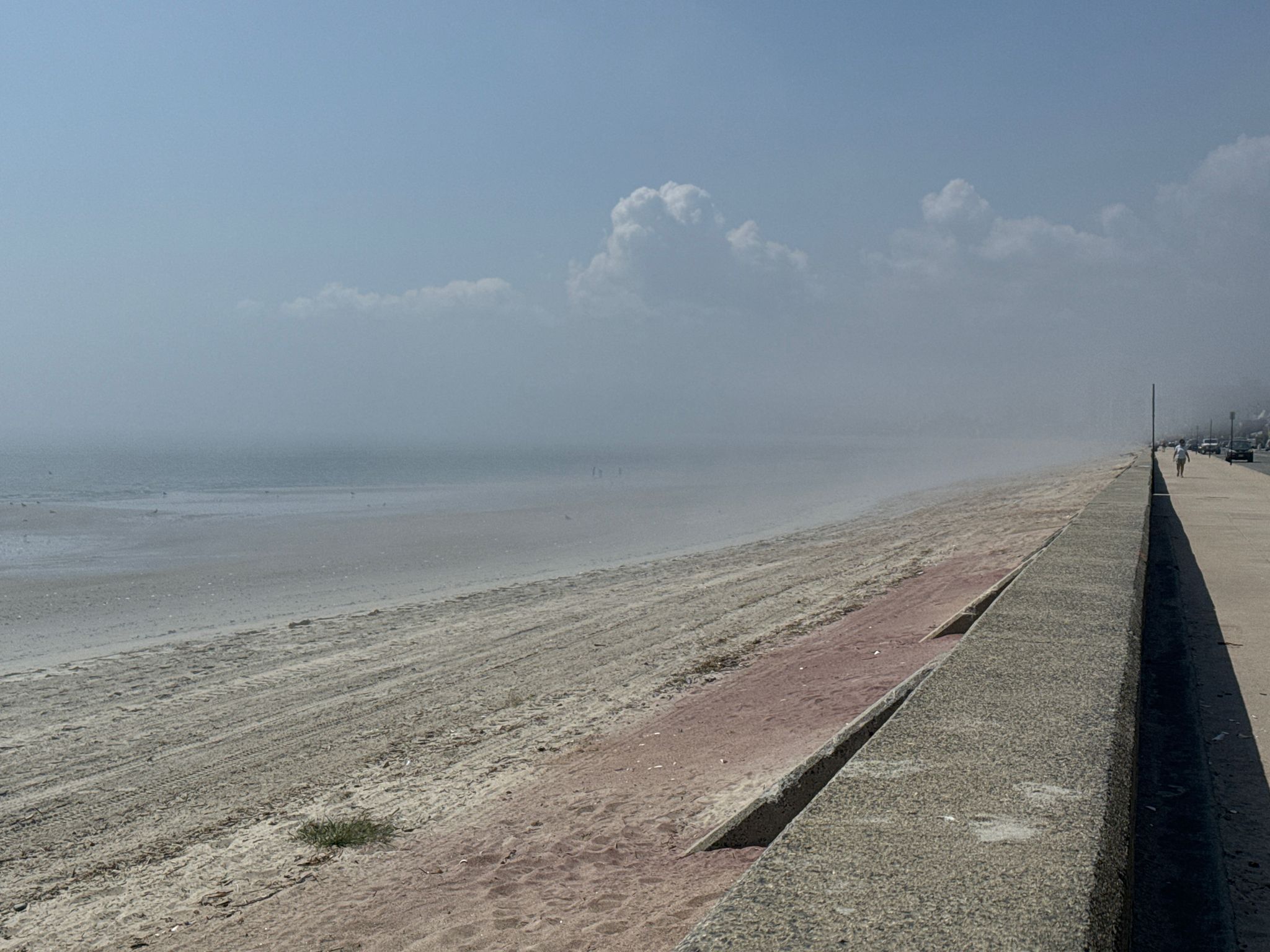 Foggy beach with a concrete barrier, hazy ocean, and soft light. - Revere Beach loop from Nahant