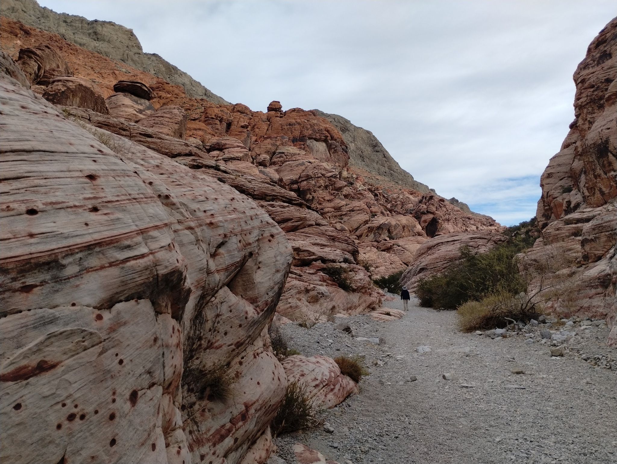 Person walks along a rocky canyon path under an overcast sky. - Kraft Mountain Loop Trail