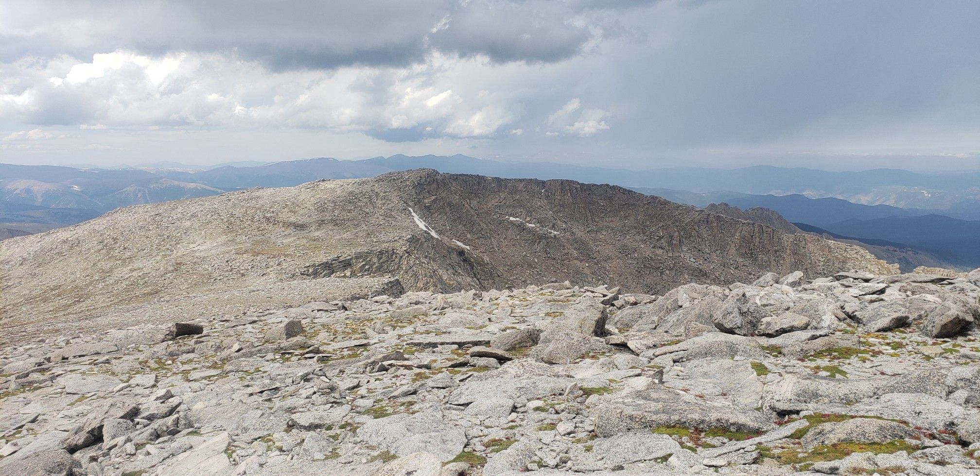 A rugged, rocky mountain peak under a dramatic cloudy sky. - Mount Blue Sky Ridge Trail