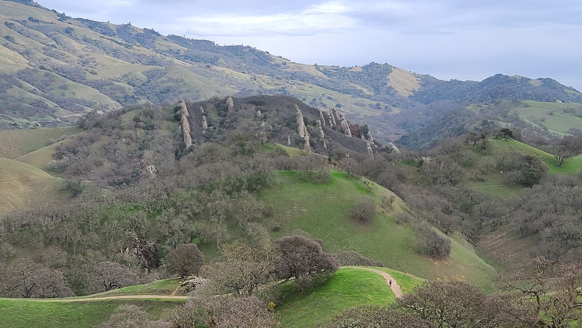 Unique rock formations on green hills with a person walking on a path. - Shell Ridge and Fairy Lantern Loop