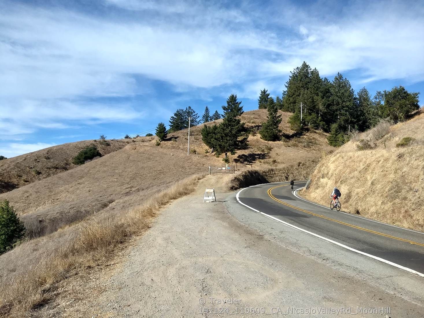 Winding road through dry hills with scattered trees and a cyclist. - Moon Hill Trail 🏞️ – School Trailhead (east) loop from Lagunitas-Forest Knolls