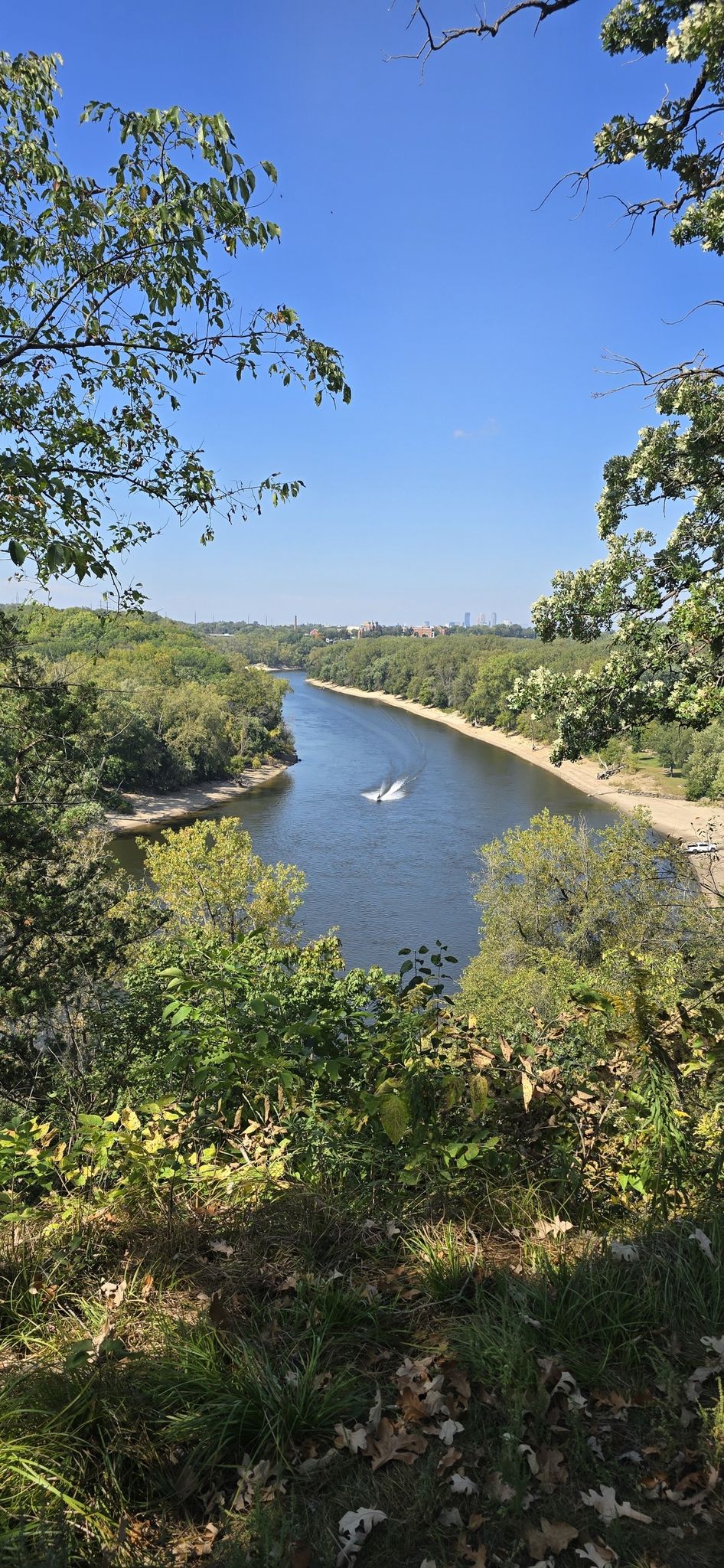 Elevated view of a wide river winding through lush green forests on a clear day. - Saint Paul Grand Round