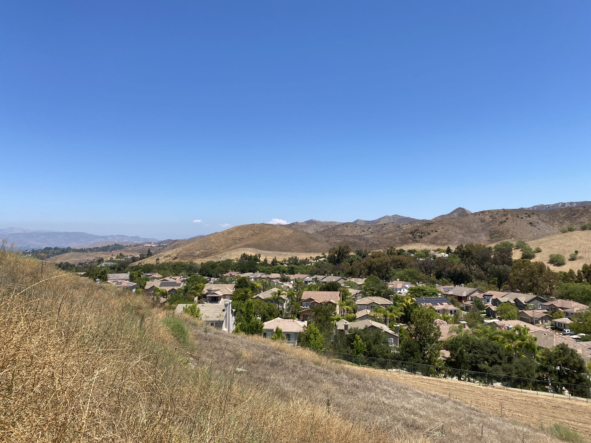 Residential area with green trees nestled in dry hills under a clear sky. - Canyon View and Wood Ranch Loop