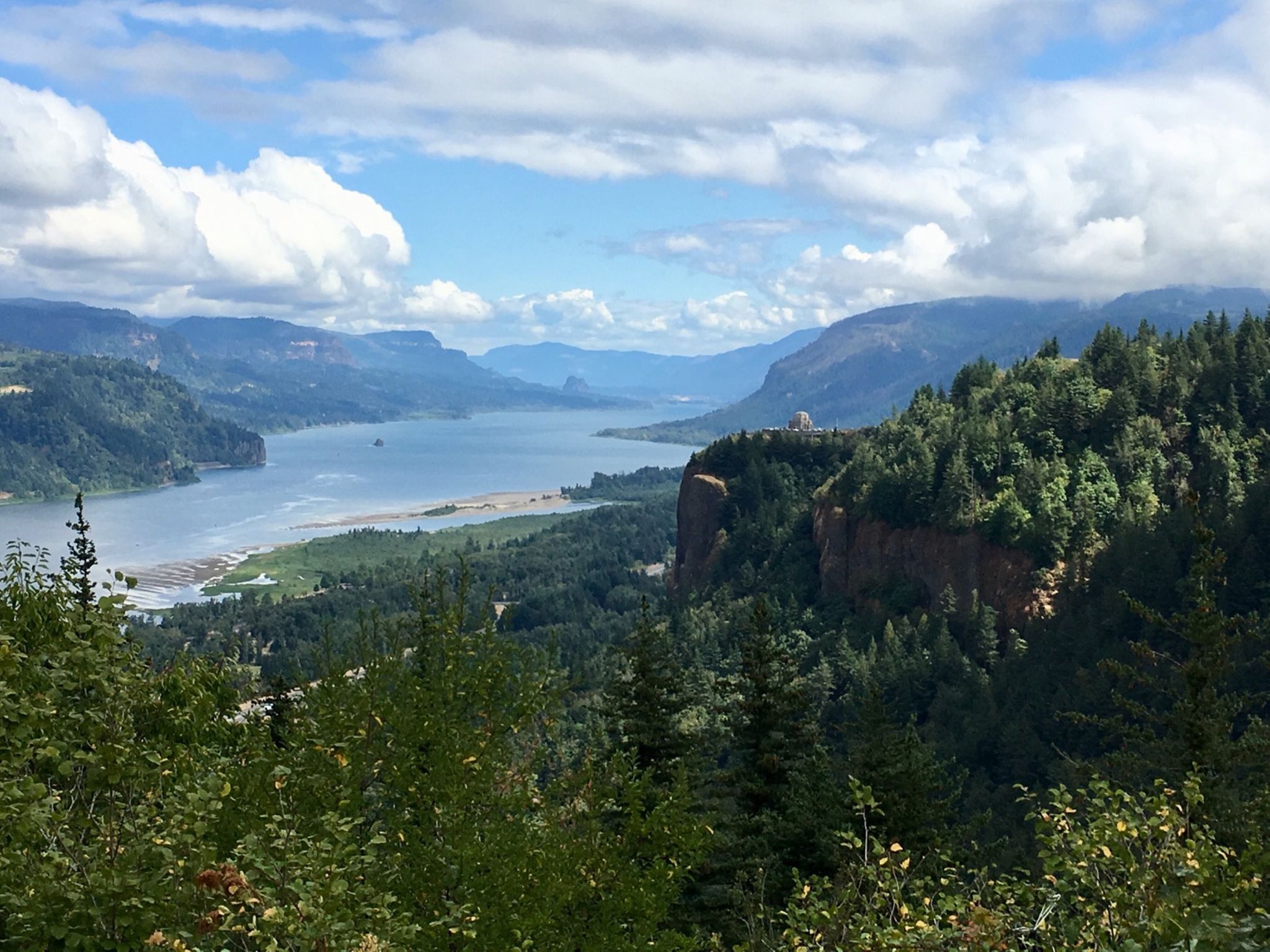 Panoramic view of a wide river winding through forested mountains under a cloudy sky. - Larch Mountain