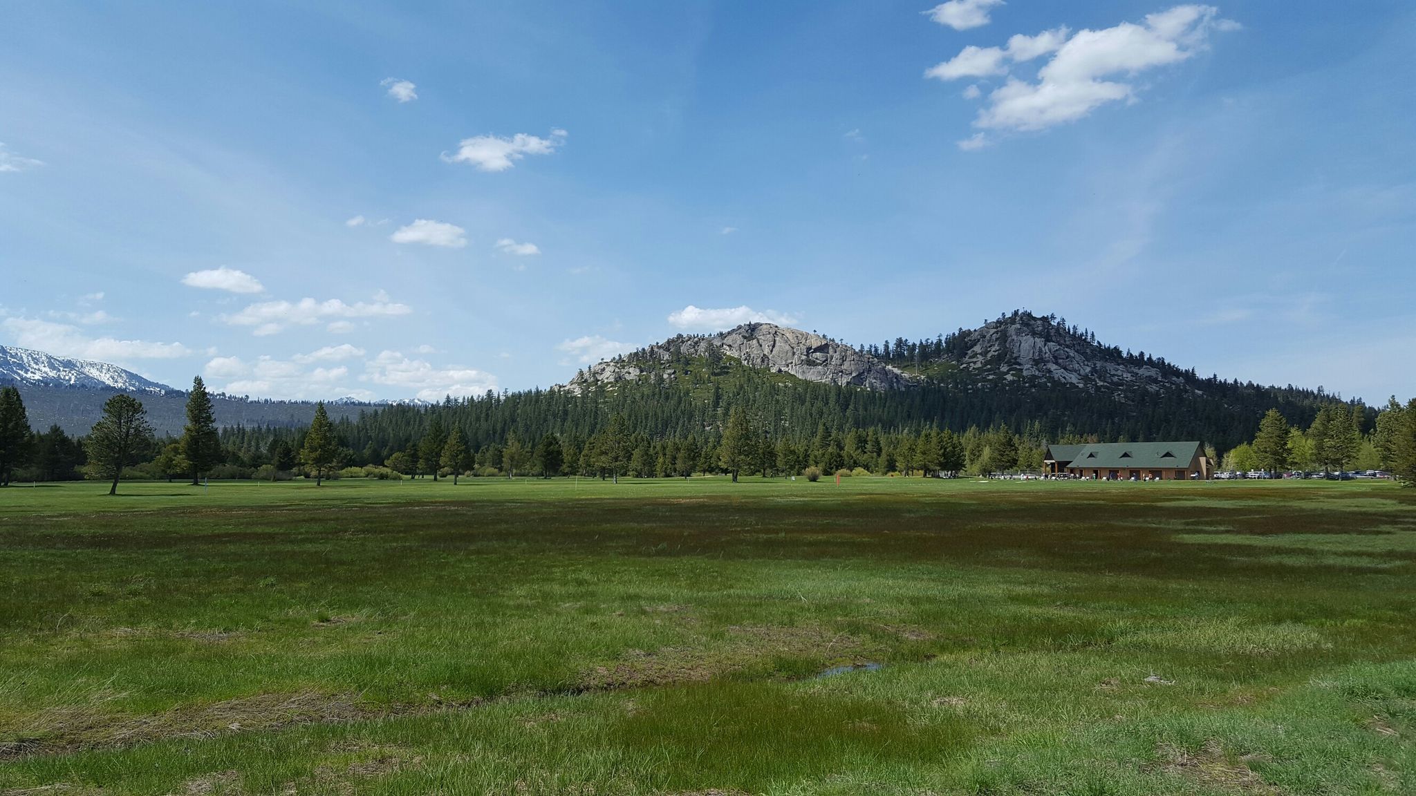 Expansive green meadow with a distant building, pine forest, and rocky mountains. - Upper Truckee River Bike Path – South Lake Tahoe Beach loop from Van Sickle Bi-State Park