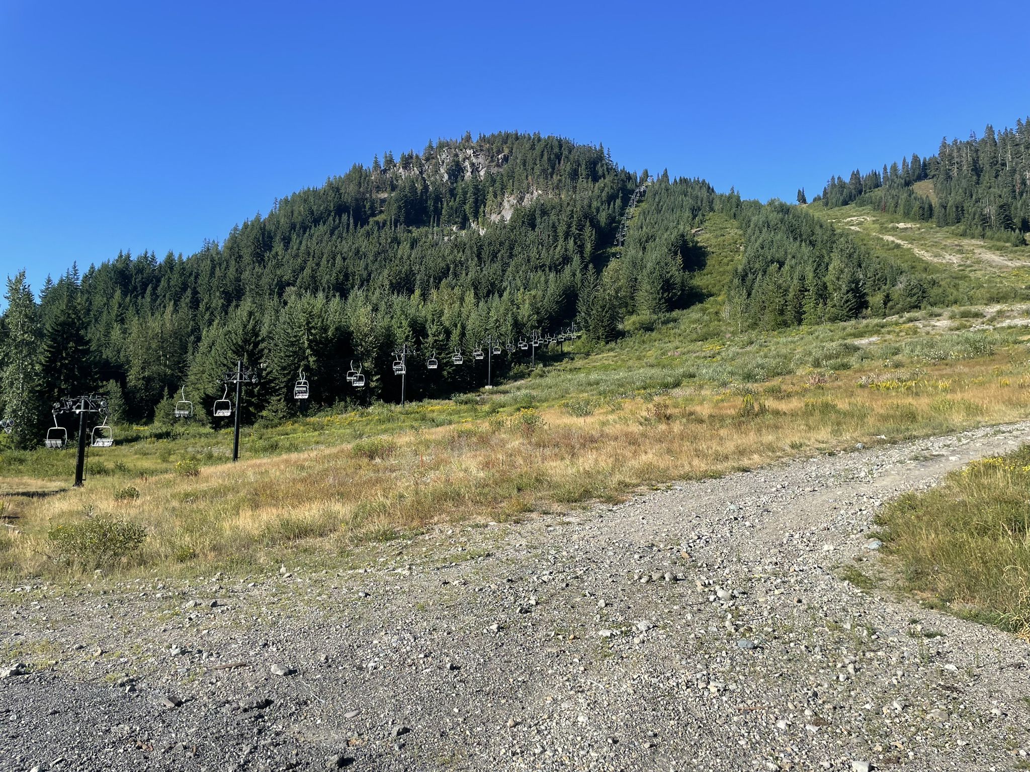 Empty ski lift chairs ascending a grassy mountain slope under clear skies. - Snoqualmie Tunnel – Snoqualmie Tunnel loop from Snoqualmie Pass