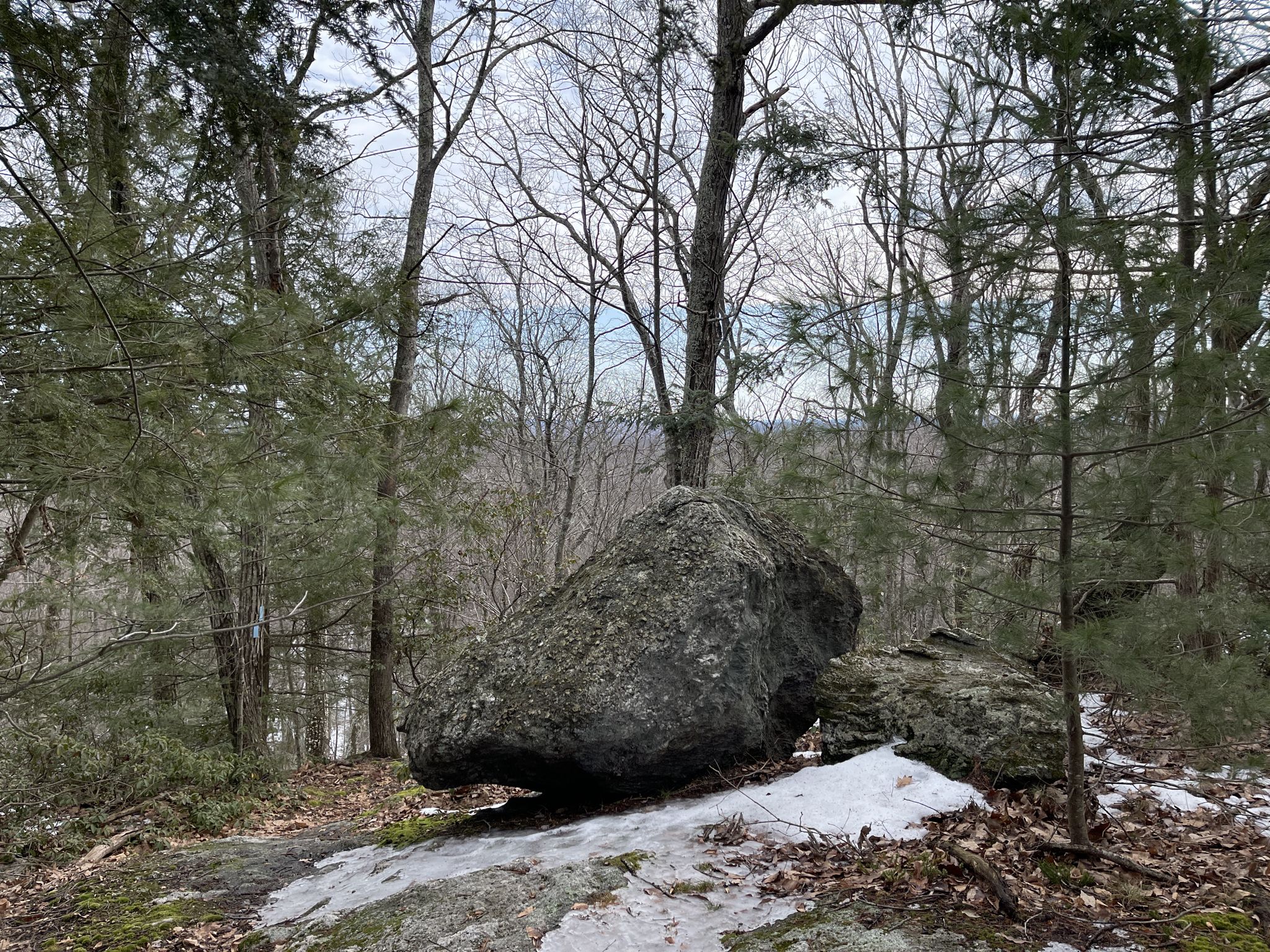 Large mossy boulder sits on a rocky outcrop in a winter forest. - Queen Mary Ledge via Tipping Rock Trail
