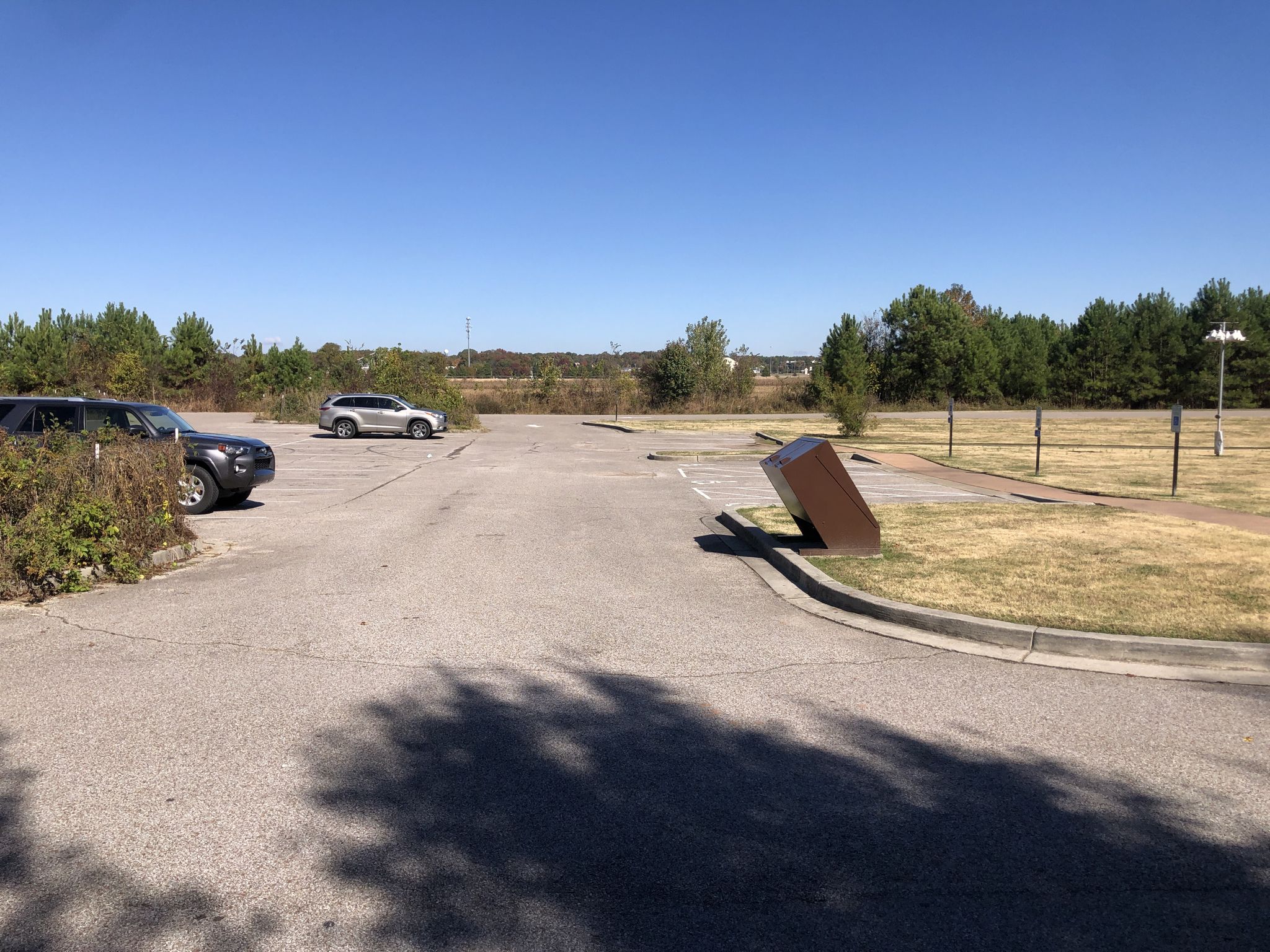 An empty paved parking lot with a few cars under a clear sky. - Mountainbike loop from Temple Israel