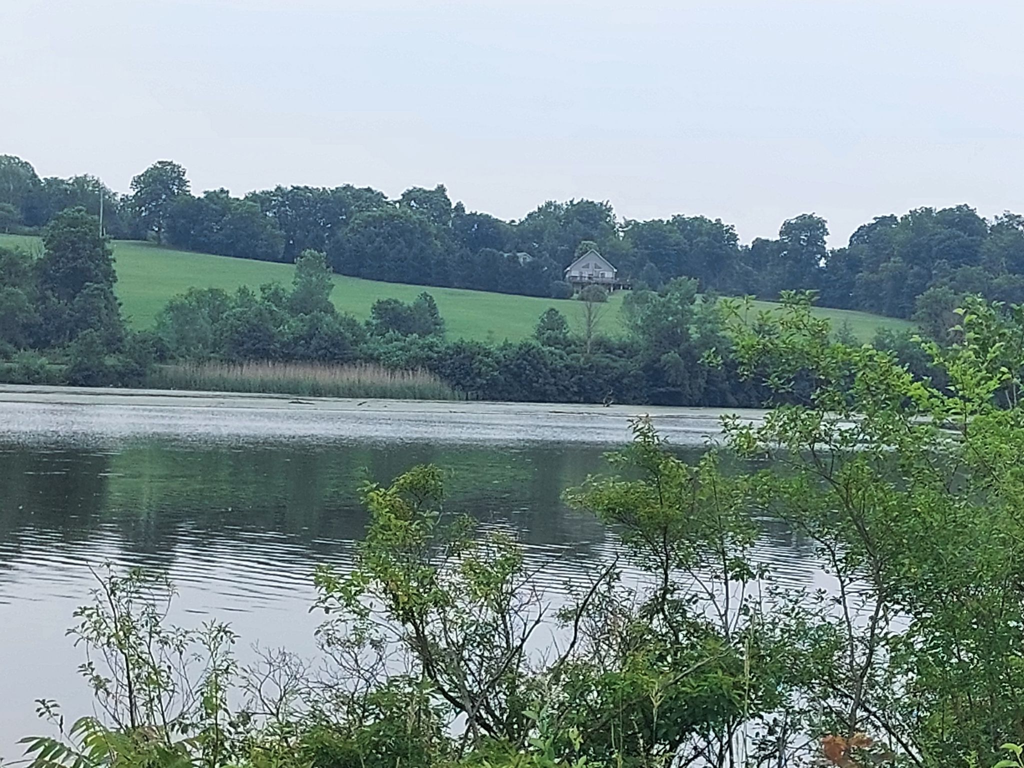 Overcast view of a calm lake with green hills and a small building. - Johnstown to St. Johnsville loop
