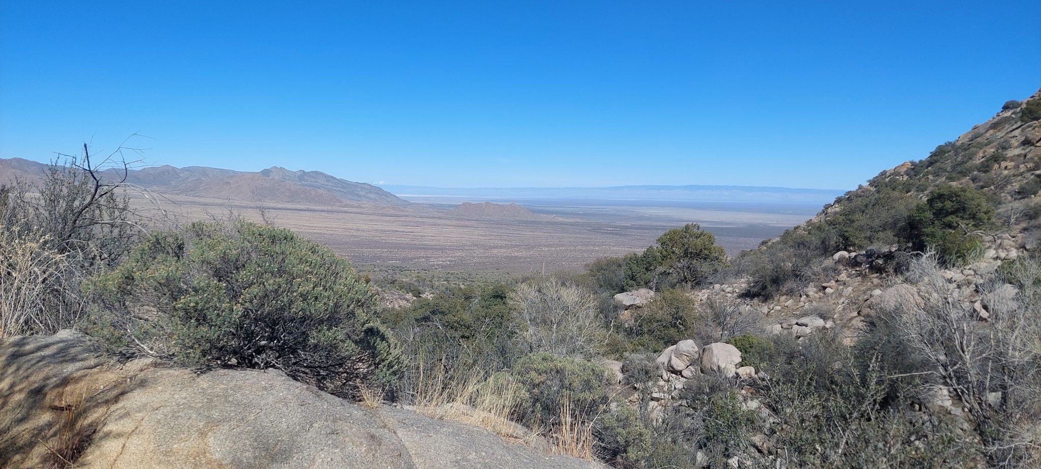 Wide desert valley and distant mountains under a clear blue sky. - Indian Hollow and Pine Tree Loop Trail