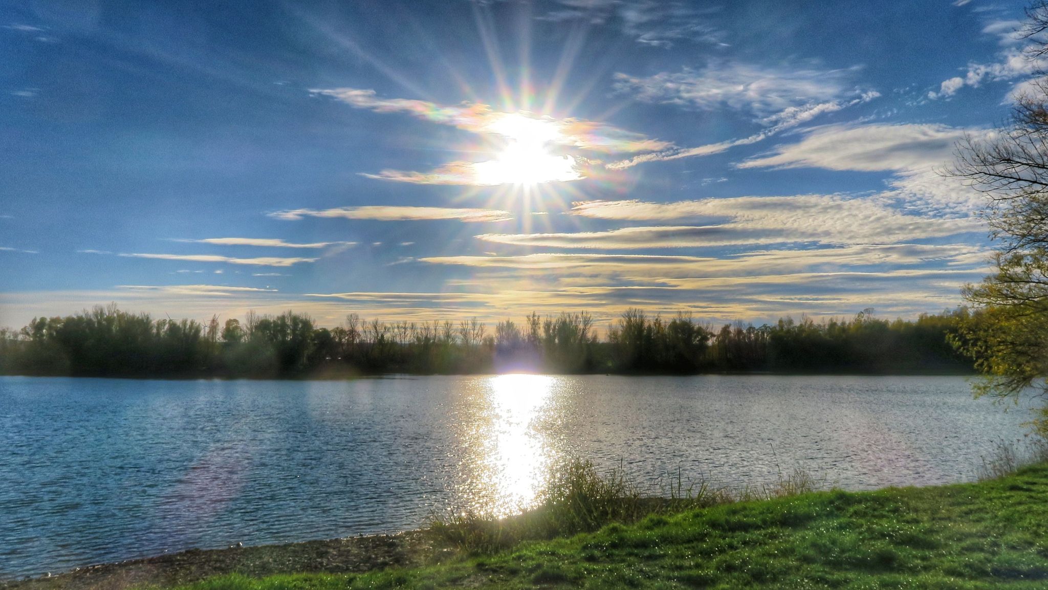 die Sonne spiegelt sich im Kiesteich