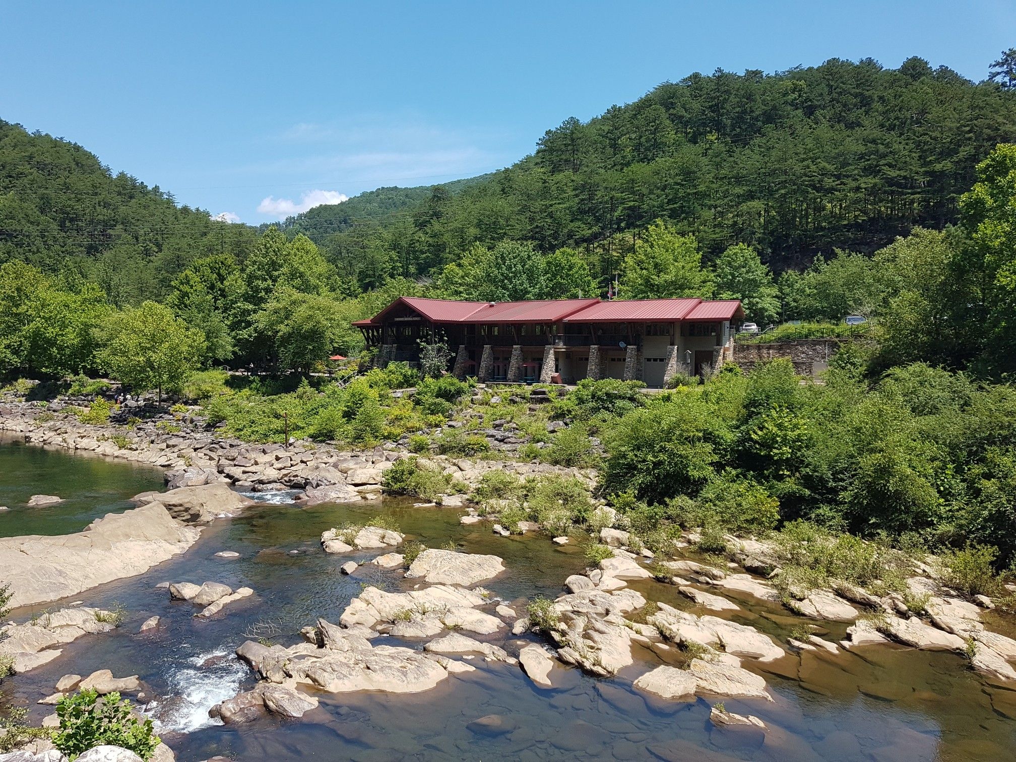 Building with red roof by a rocky river, surrounded by green hills. - Whitewater River – Ocoee Number Three loop from Ocoee Number Three Lake