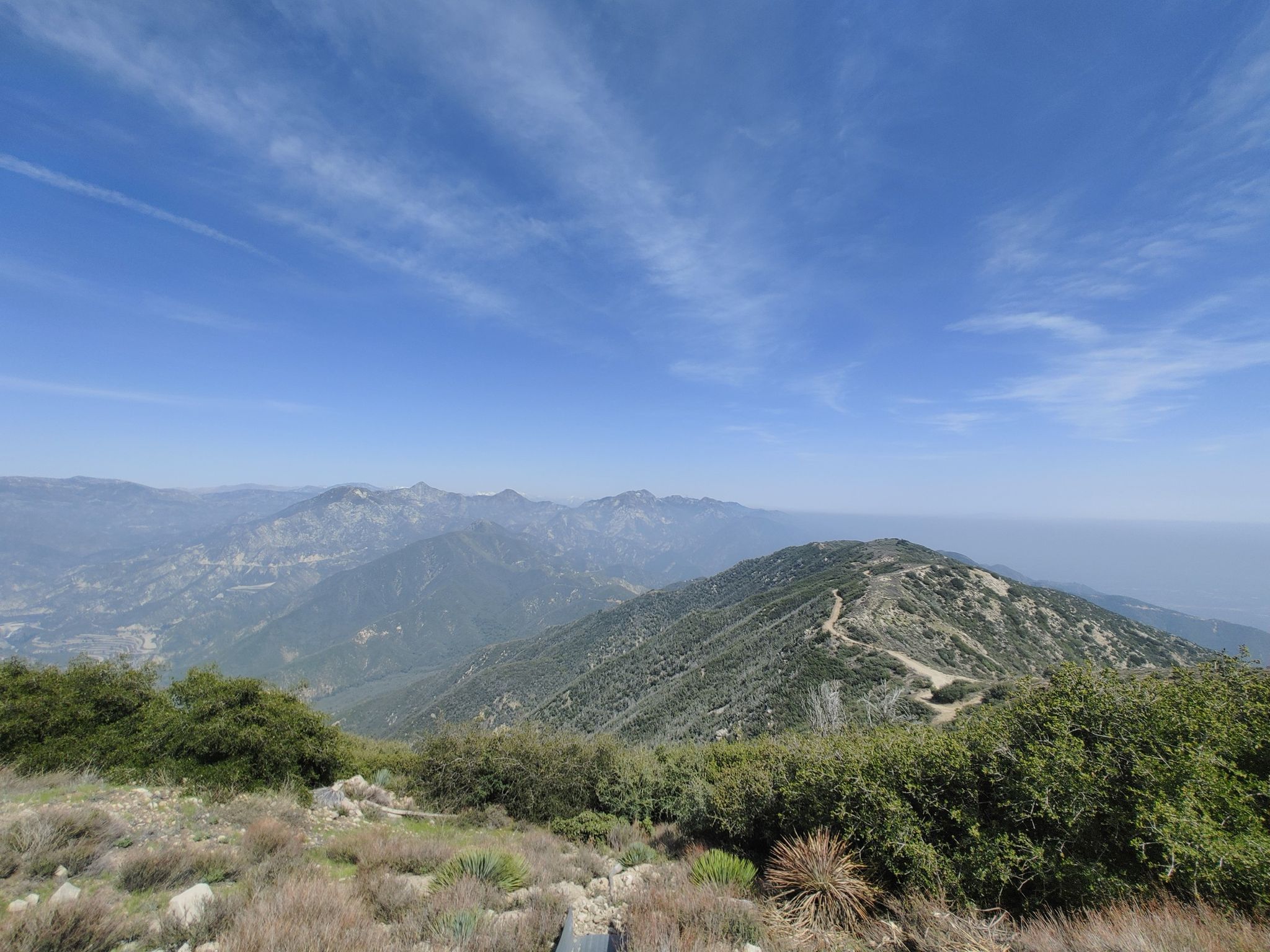 Expansive mountain landscape with a winding dirt road under a clear blue sky. - Mount Lukens via Earl Canyon Trail