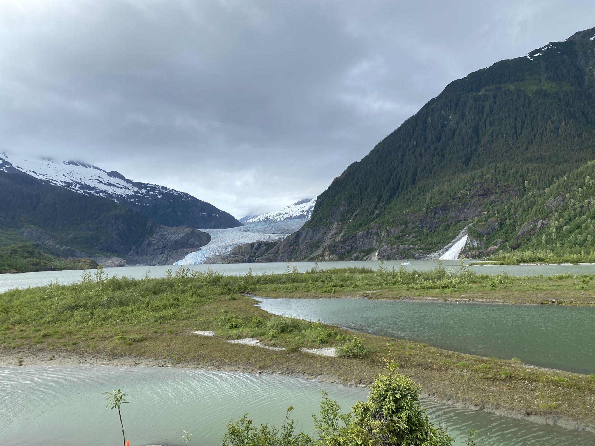 A wide glacier between mountains, with a waterfall and green islands in the lake. - Cope Park – Mendenhall Glacier Viewpoint loop from Juneau