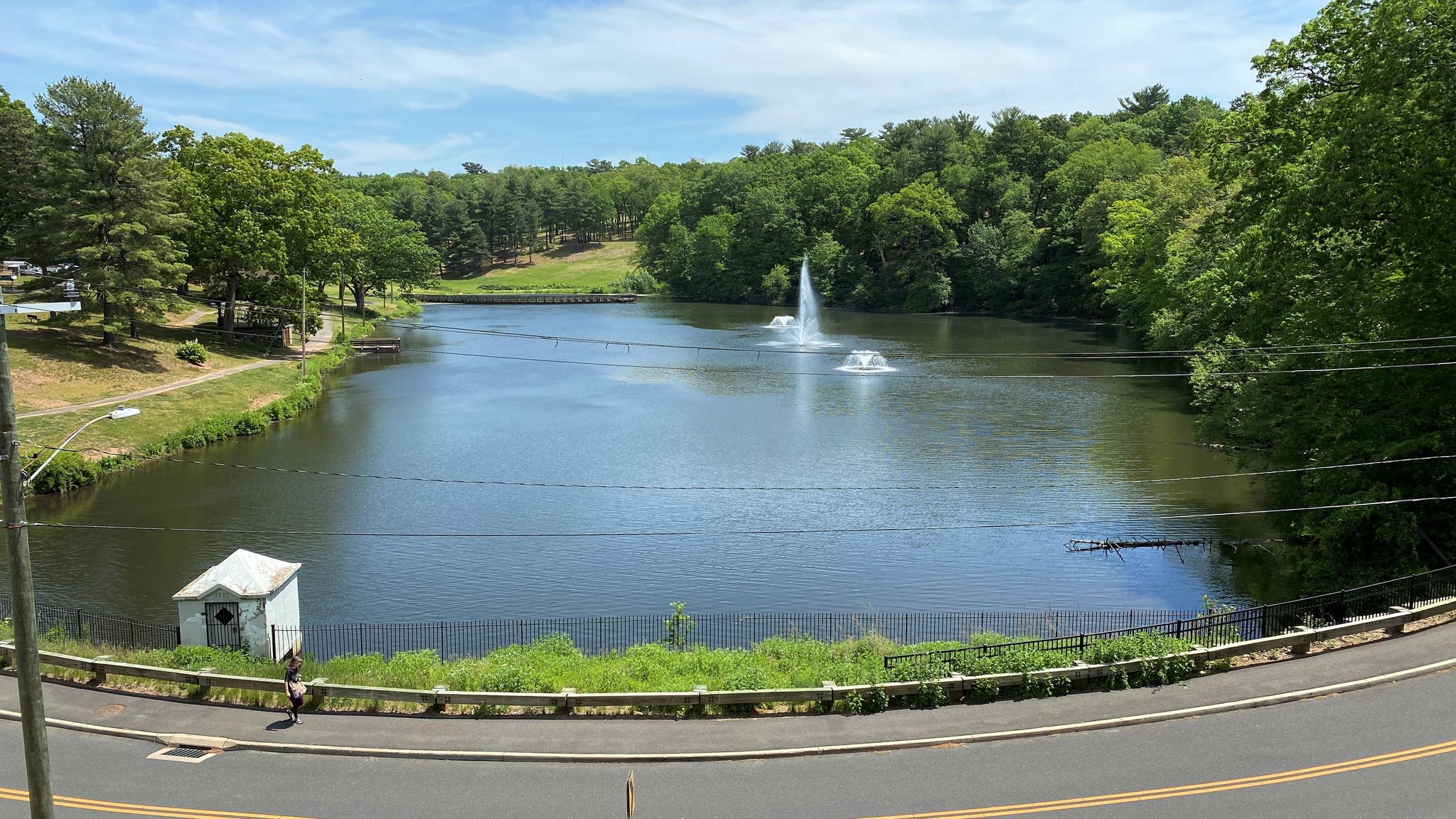 A wide lake with two fountains, surrounded by green trees on a sunny day. - Cheney Rail Trail