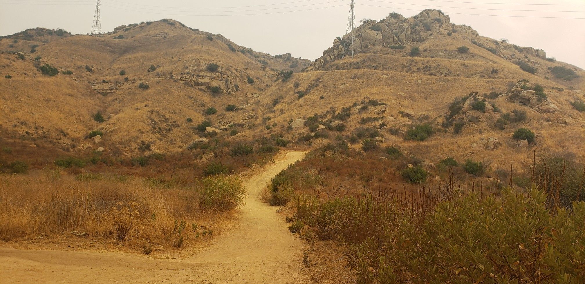 A dirt road leads up to dry, rocky hills under an overcast sky. - Cheeseboro Ridge and Cheeseboro Canyon Loop