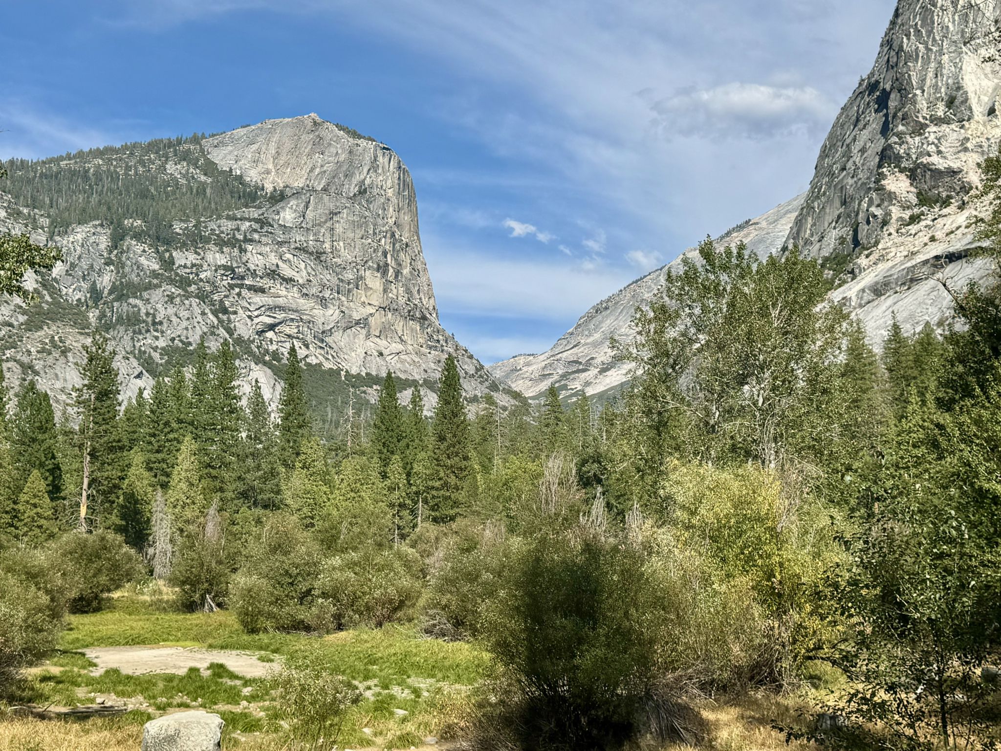 Bright valley with towering rocky cliffs, green forest, and clear blue sky. - Yosemite Village to Mirror Lake