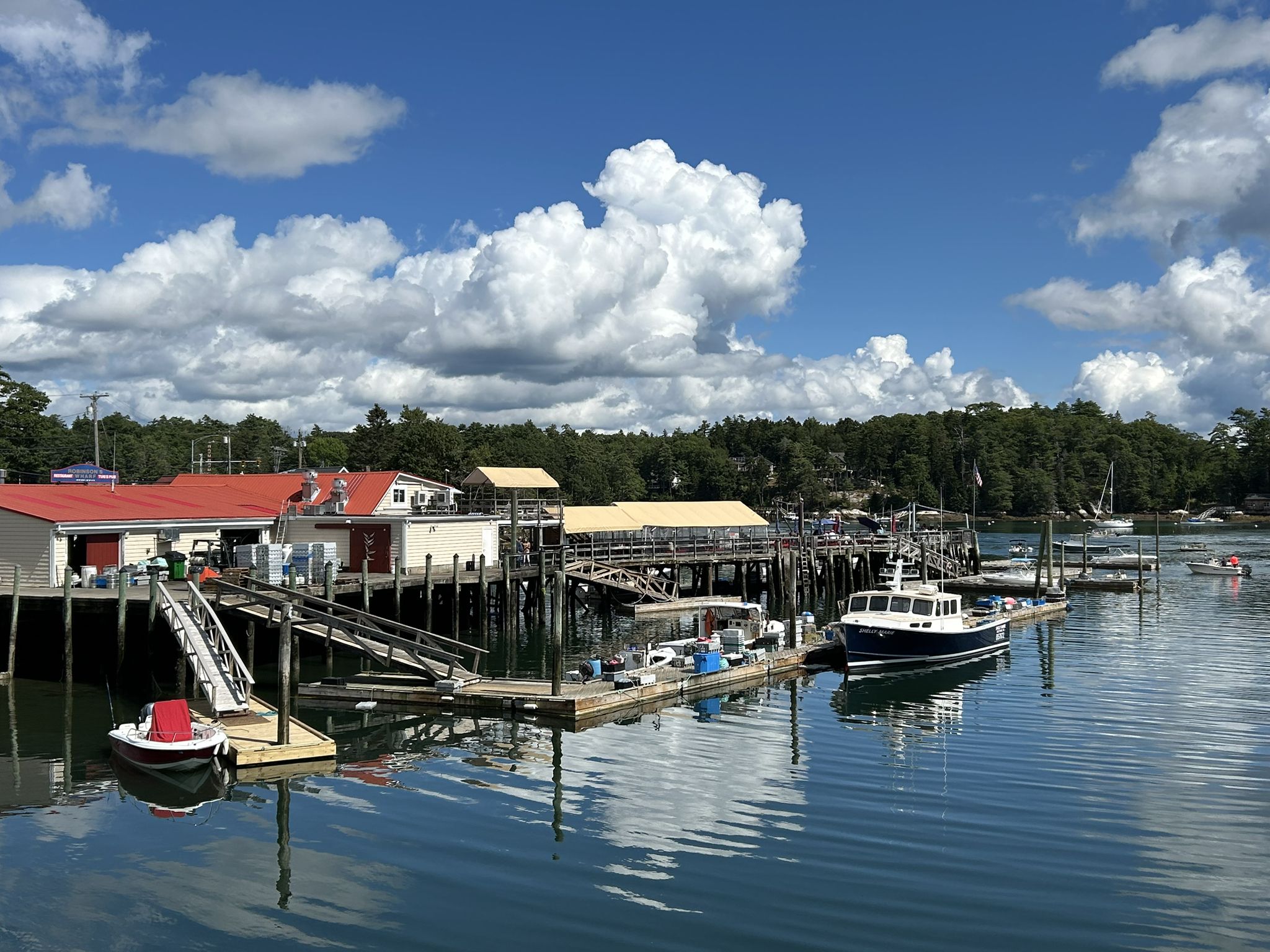 Sunny marina scene with boats docked at wooden piers and waterfront buildings. - Deckers Cove – School Pond loop from Southport