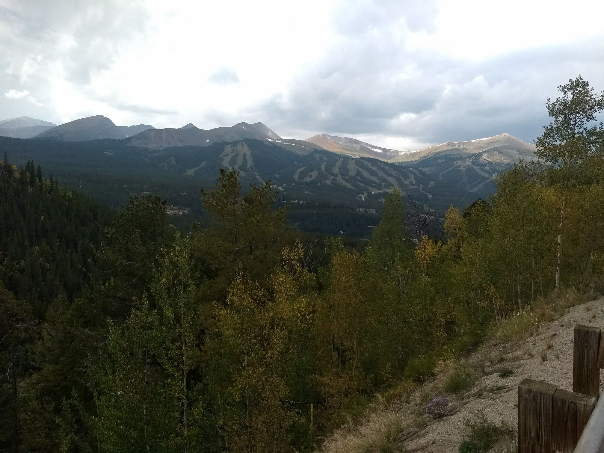 Overcast mountain range with forested slopes and patches of snow under a cloudy sky. - Breckenridge Overlook loop