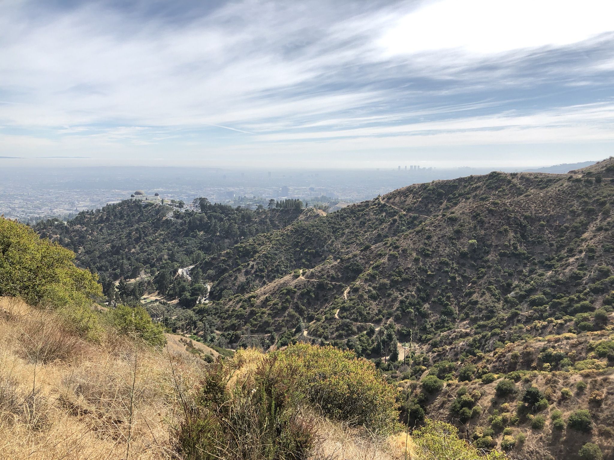 Hazy panoramic view of a city and hills under a cloudy sky. - Mount Hollywood Summit – Glendale Peak loop from Los Angeles Zoo