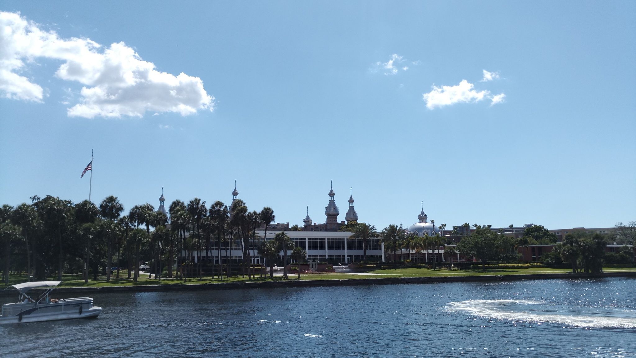 Large domed building and palm trees by a river under bright blue sky. - Tampa Riverwalk