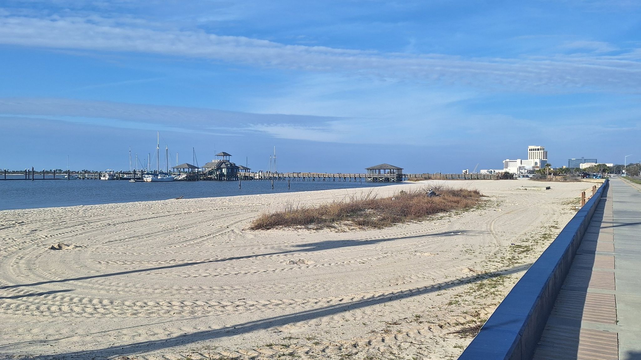 Expansive sandy beach next to water with distant boats under a clear blue sky. - Biloxi Bay Bridge – Oversized guitar loop from Ocean Springs