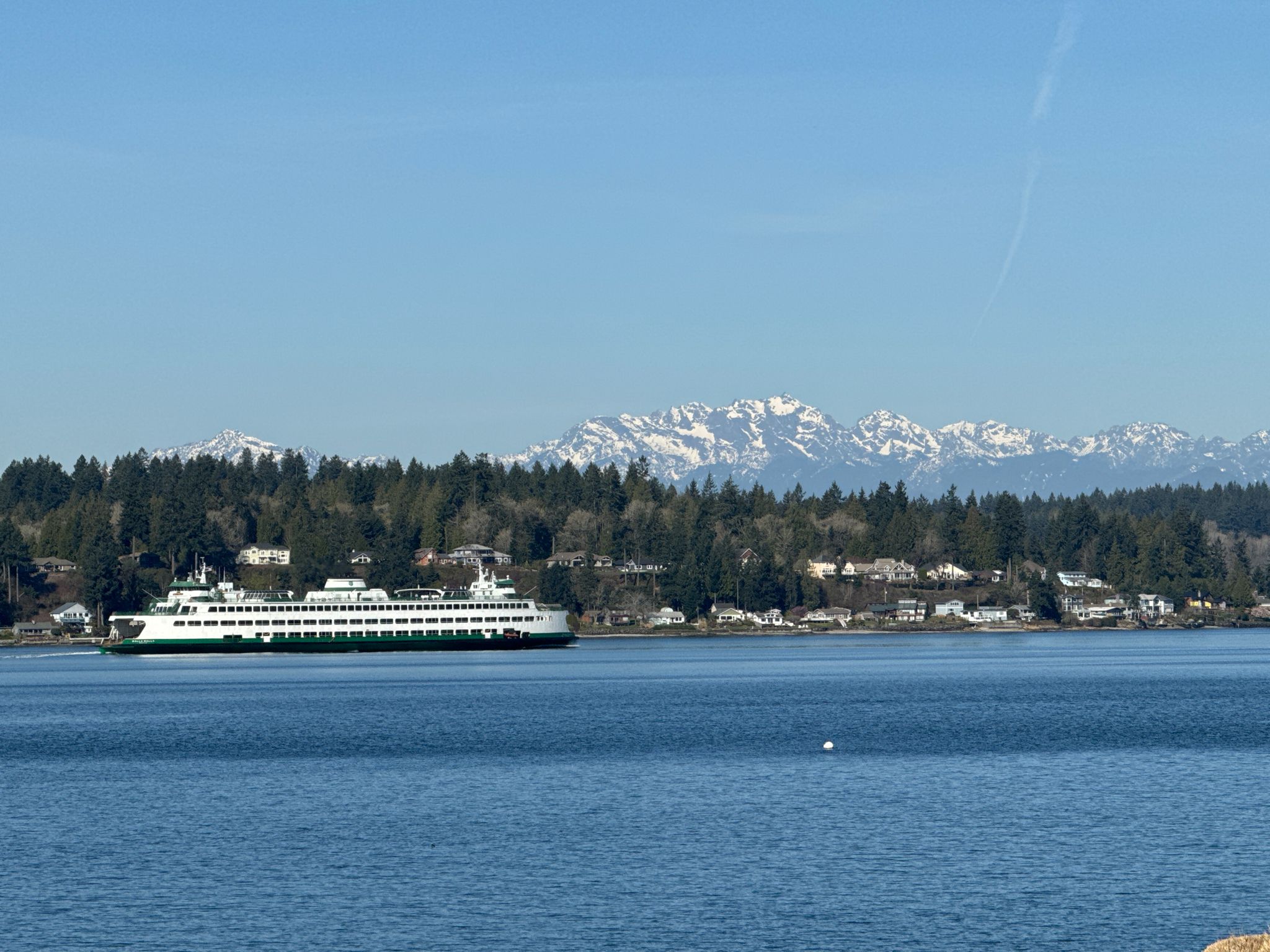 Large ferry boat on blue water, forested shoreline, and snowy mountains. - Cascadia Marine Trail – Battery Vinton loop from Fort Ward Park