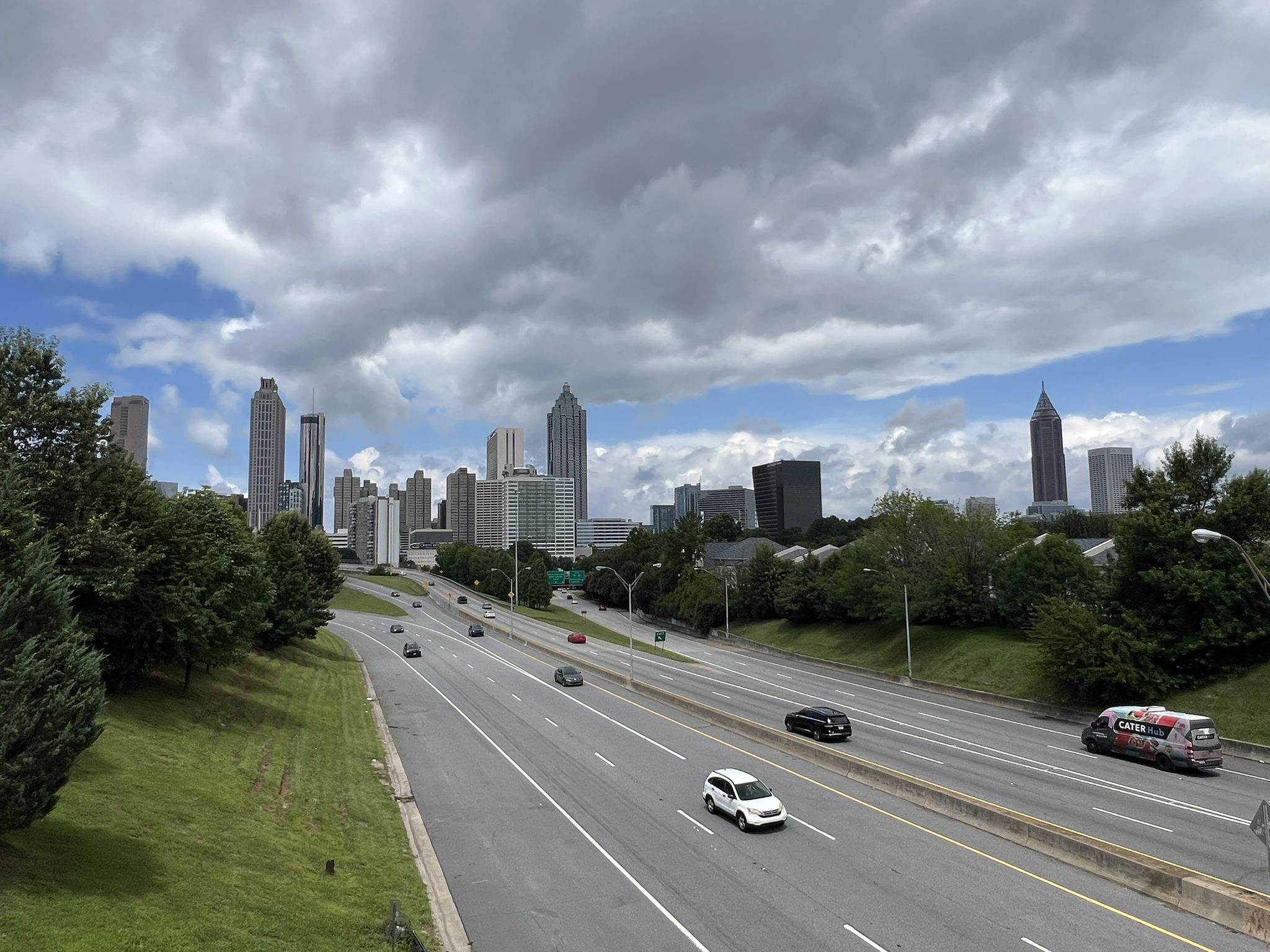 Busy highway with cars, leading towards a distant city skyline under clouds. - Stone Mountain Grist Mill – Confederate Hall loop from King Memorial