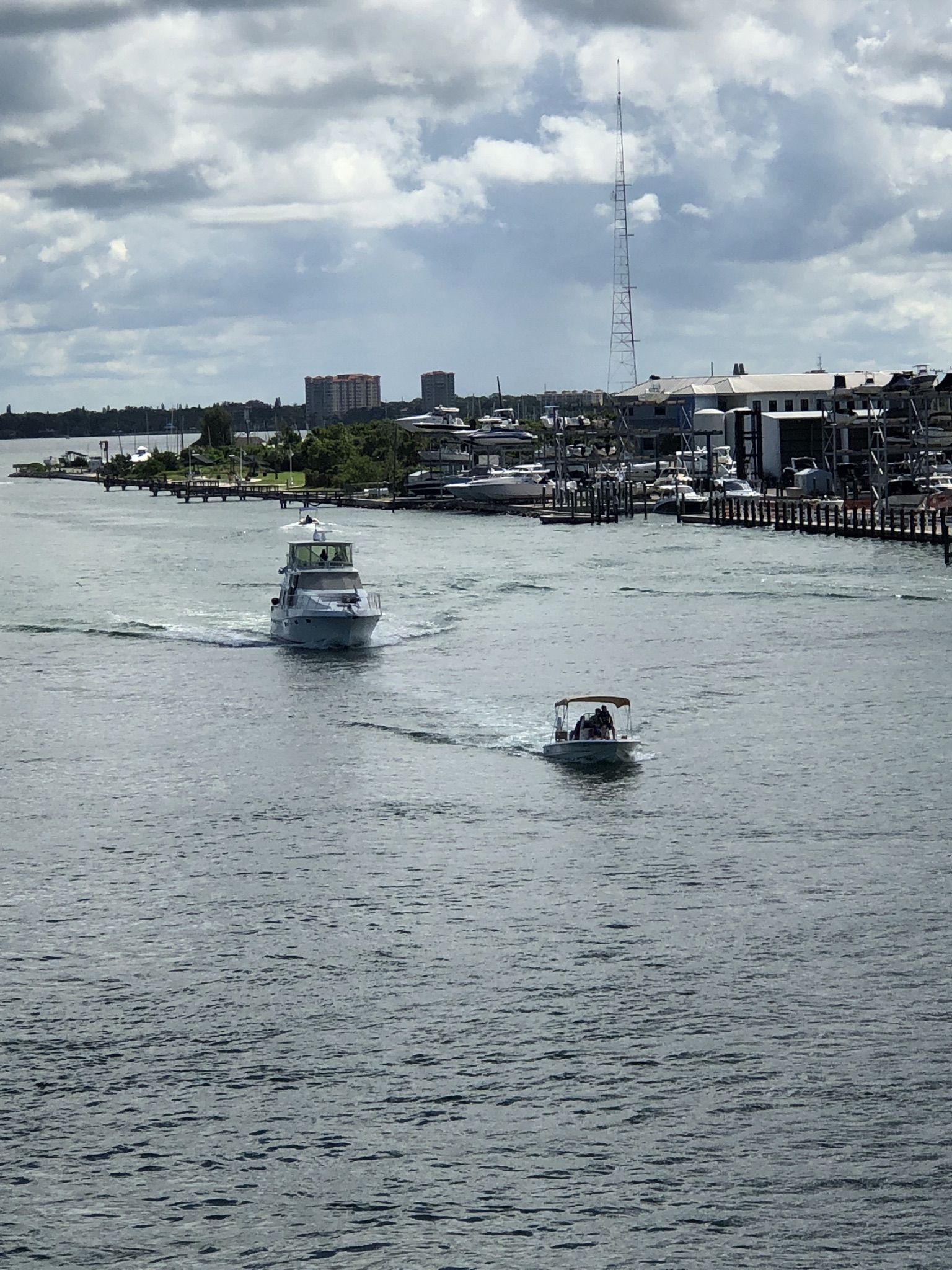 Two boats navigate calm water with distant buildings and docks under cloudy sky. - Bayfront Park – Lido Key loop from Bird Key