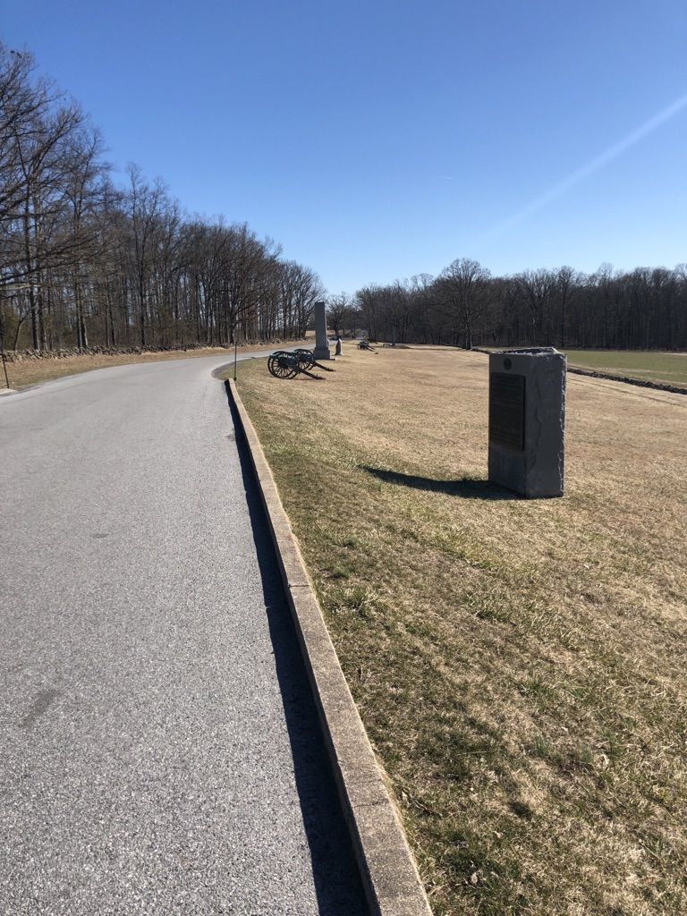 Paved road curves past dry grass, stone markers, and bare trees. - Virginia Memorial – State of Pennsylvania Monument loop from Gettysburg & Harrisburg Railroad Depot