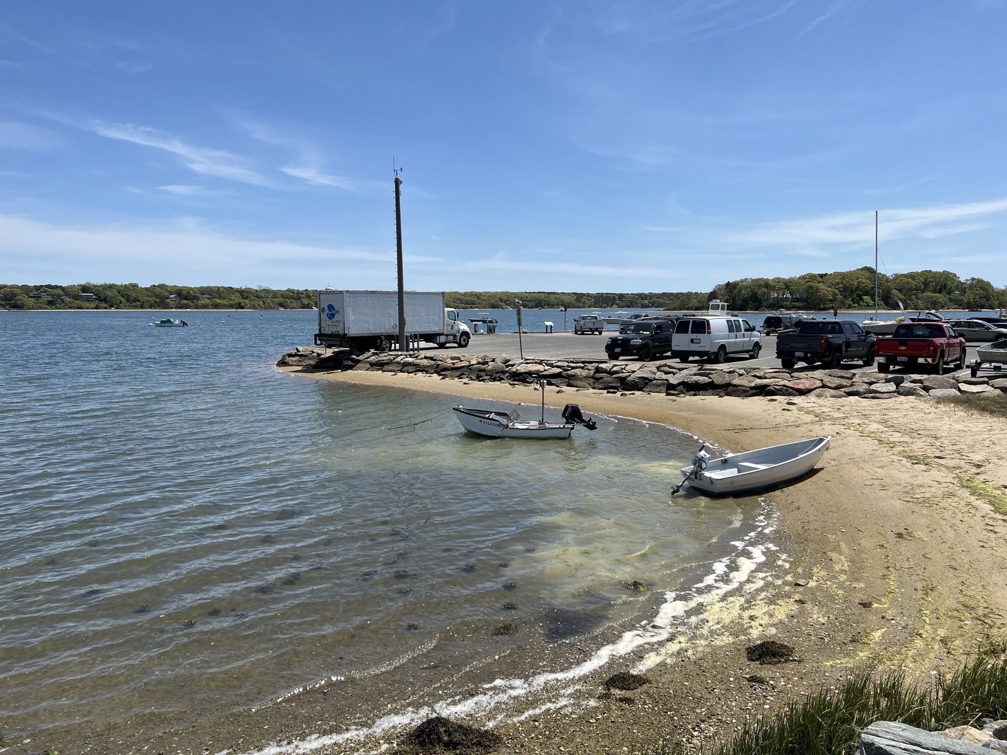 Small boats in shallow water next to a dock and parking lot. - East Chop Lighthouse – Vineyard Haven Harbor loop from Oak Bluffs