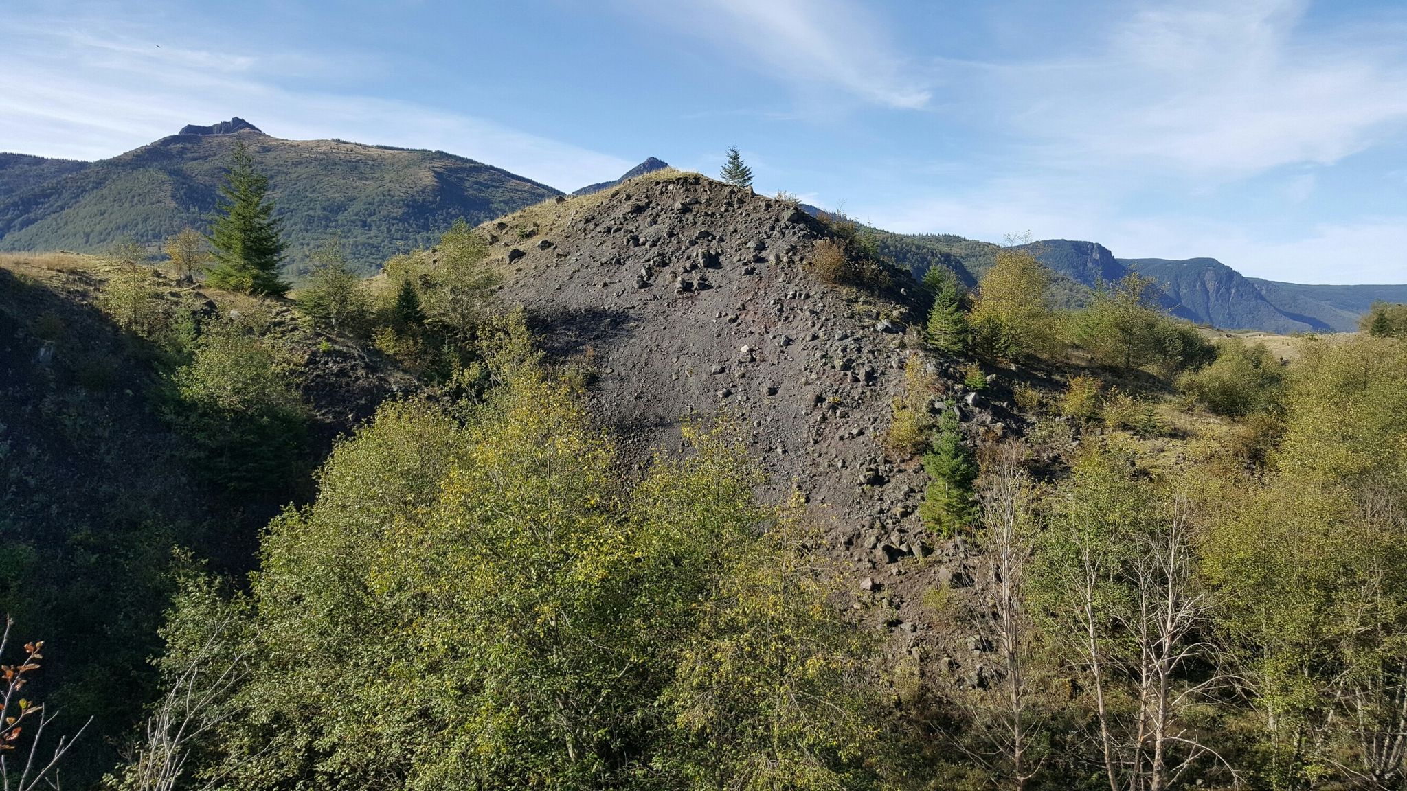 Rocky, treed hills and distant mountains under a bright blue sky. - Boundary West Trail