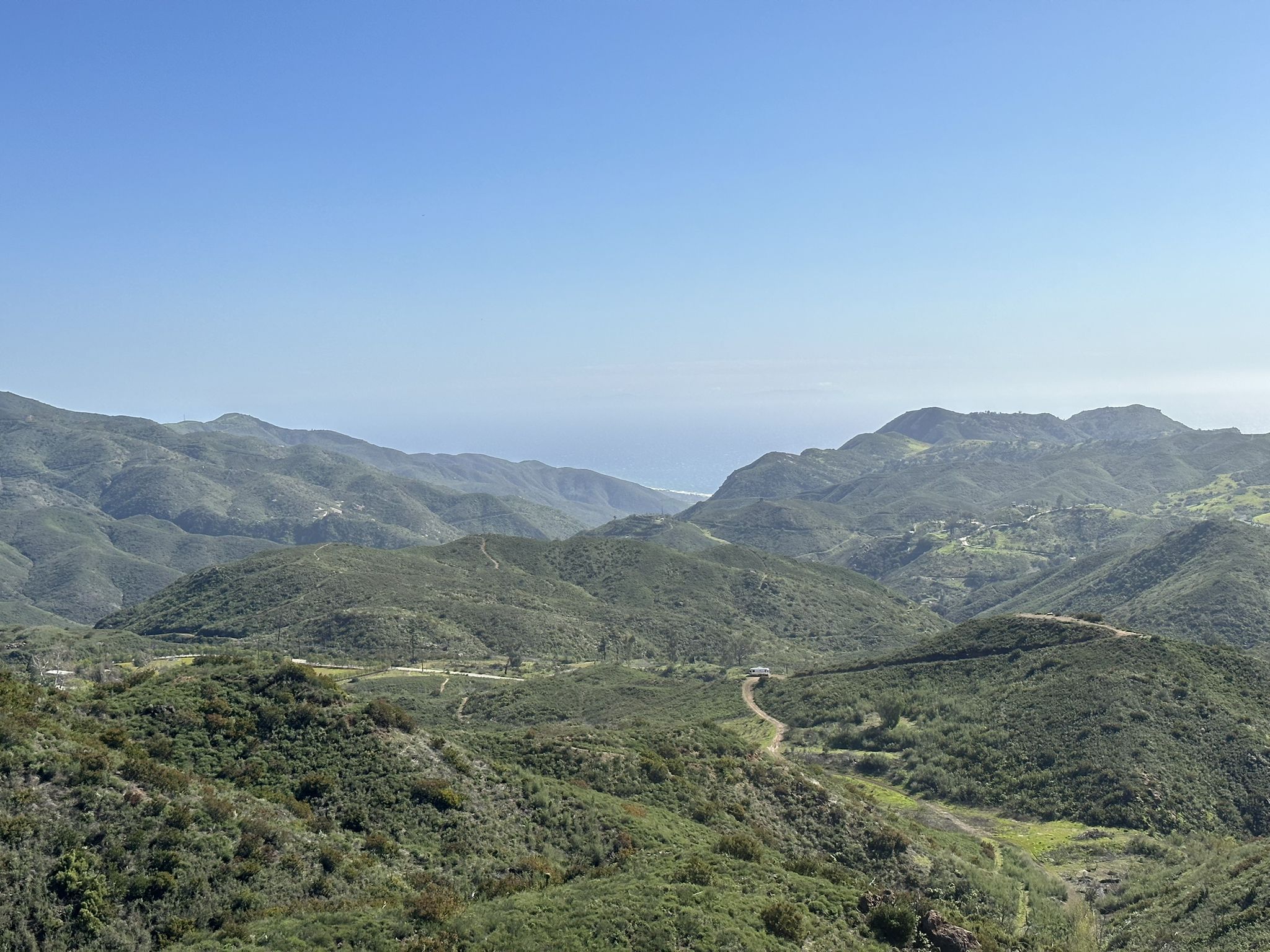 Expansive view of green rolling mountains with a distant ocean horizon. - MRCA Open Space – Long-distance hiking trail loop from Backbone Trail - Encinal to Mulholland
