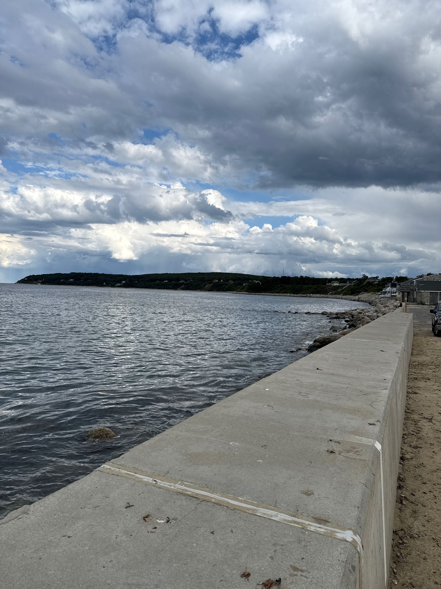 A long concrete seawall borders calm water under a cloudy sky. - Bentley Loop Trail – Charge Pond loop from Chiltonville