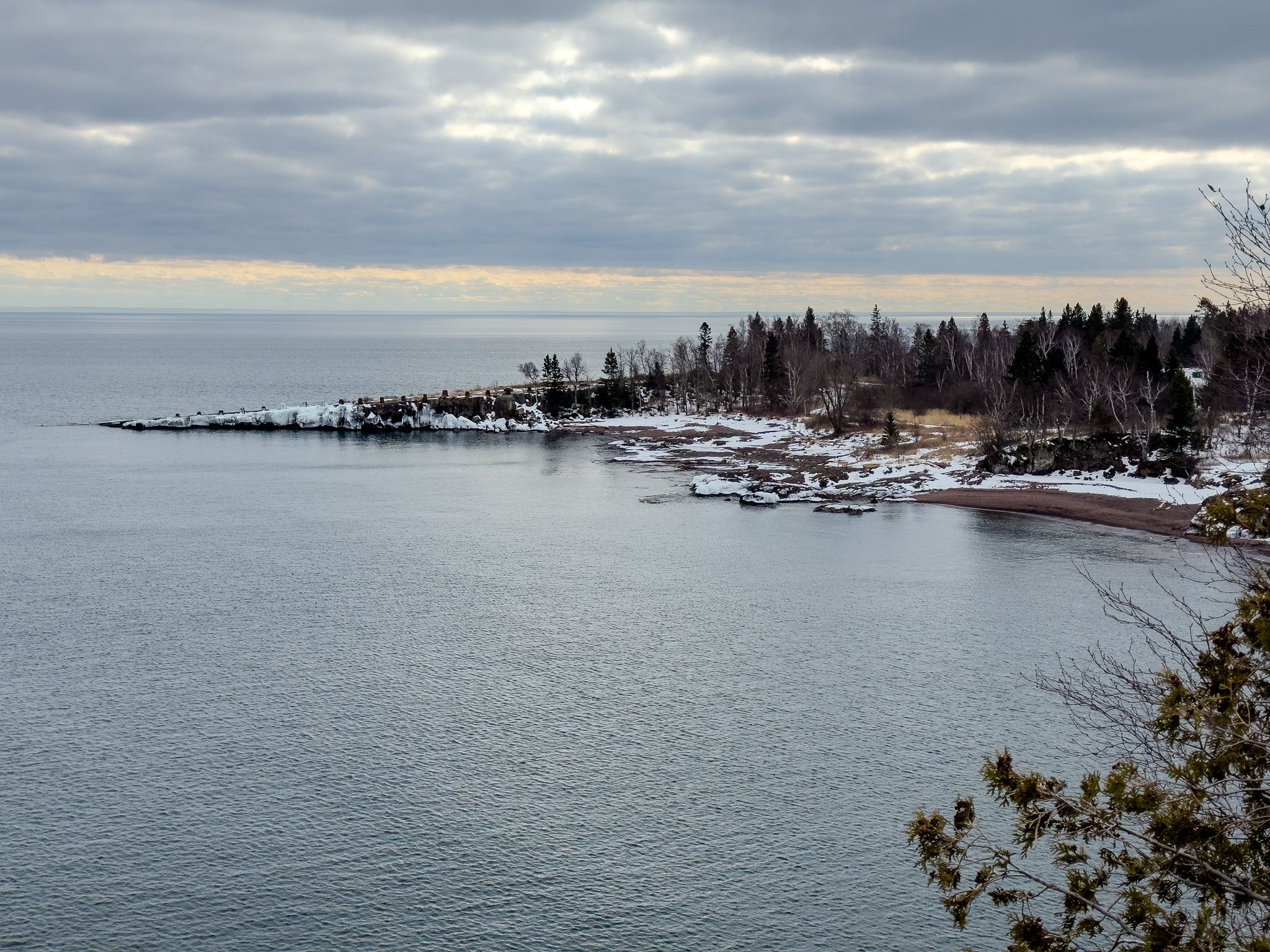 Overcast view of a large lake with a snowy, forested shoreline. - Agate Beach via Gitchi-Gami Trail