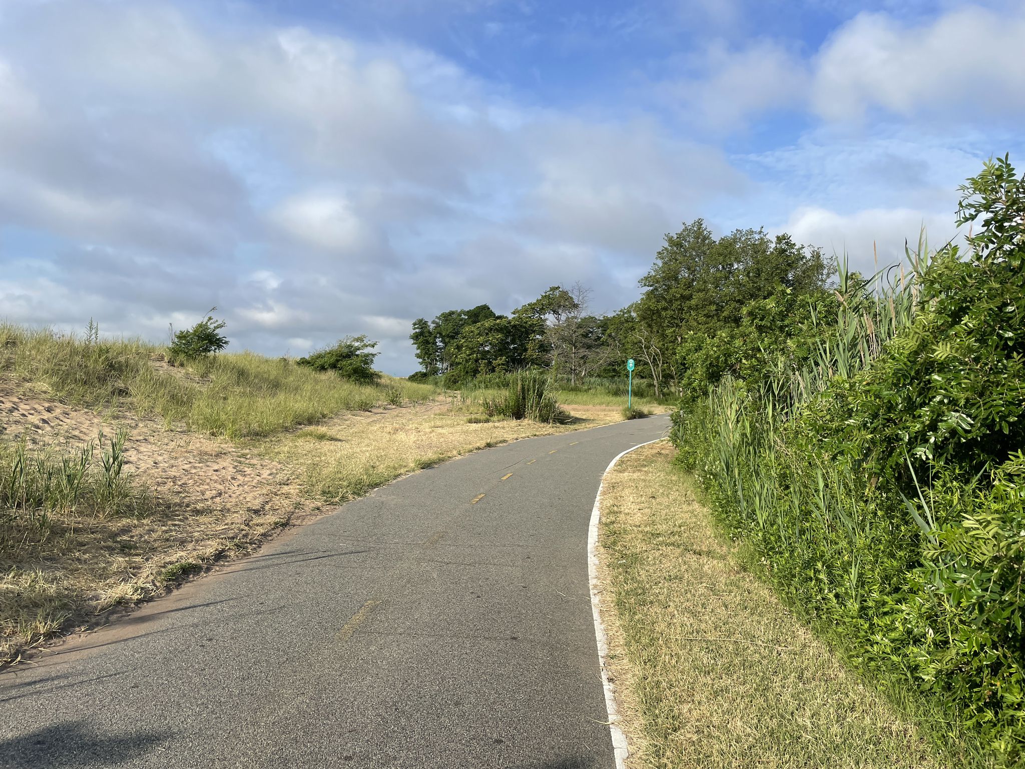 Paved path curving through grassy dunes under a partly cloudy sky. - Fort Wadsworth — Staten Island – Fort Wadsworth loop from Clifton