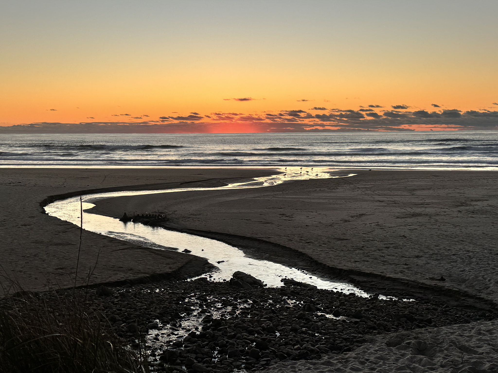 Winding stream on a sandy beach at sunset, ocean waves in background. - Hiking loop from Lincoln City