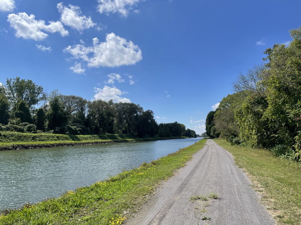 A wide canal next to a dirt path under a bright blue sky. - Erie Canalway Trail (Albion to Brockport)