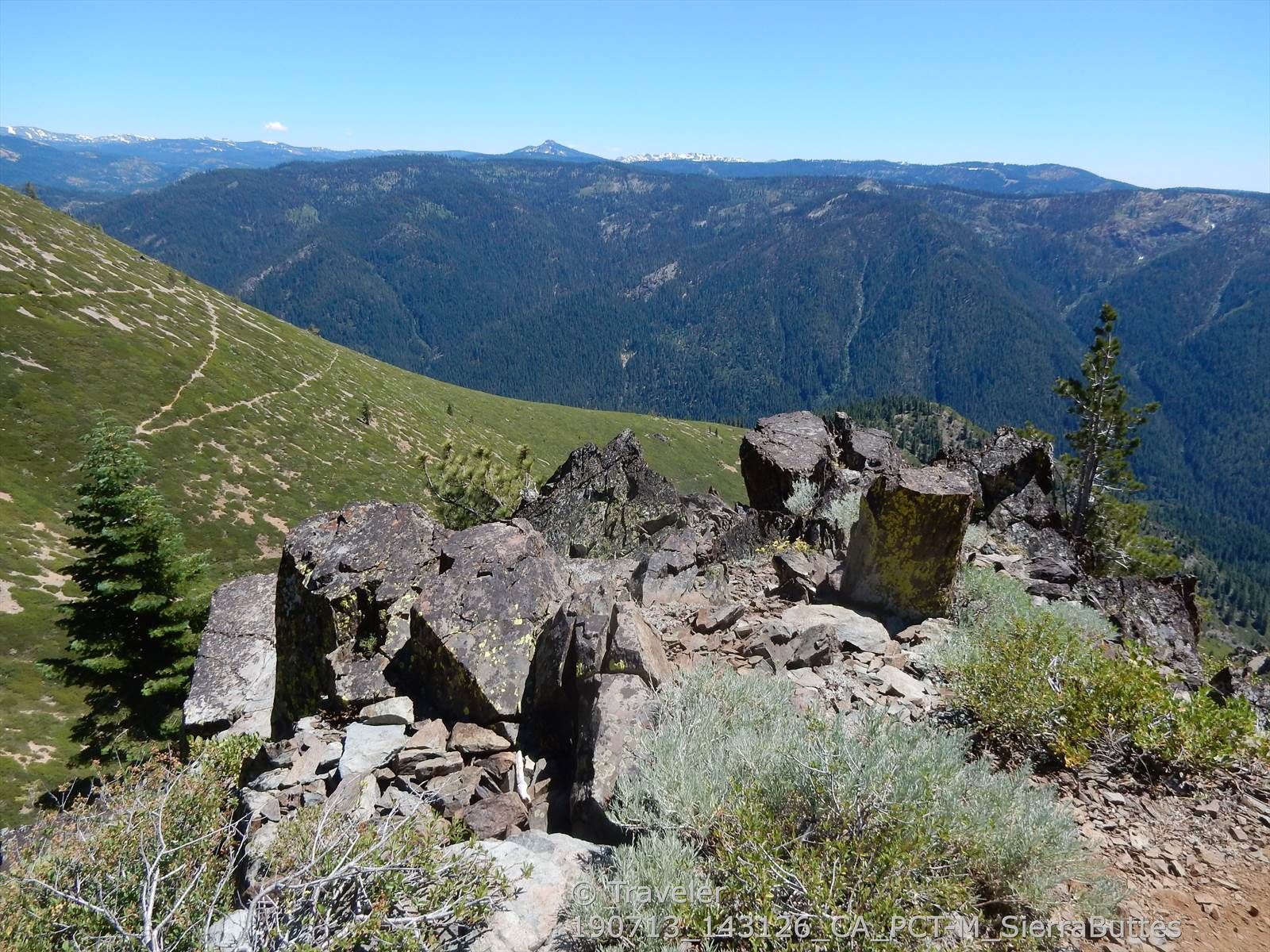 Rocky outcrop on a mountain ridge overlooking a vast forested landscape. - Sierra Buttes Trail
