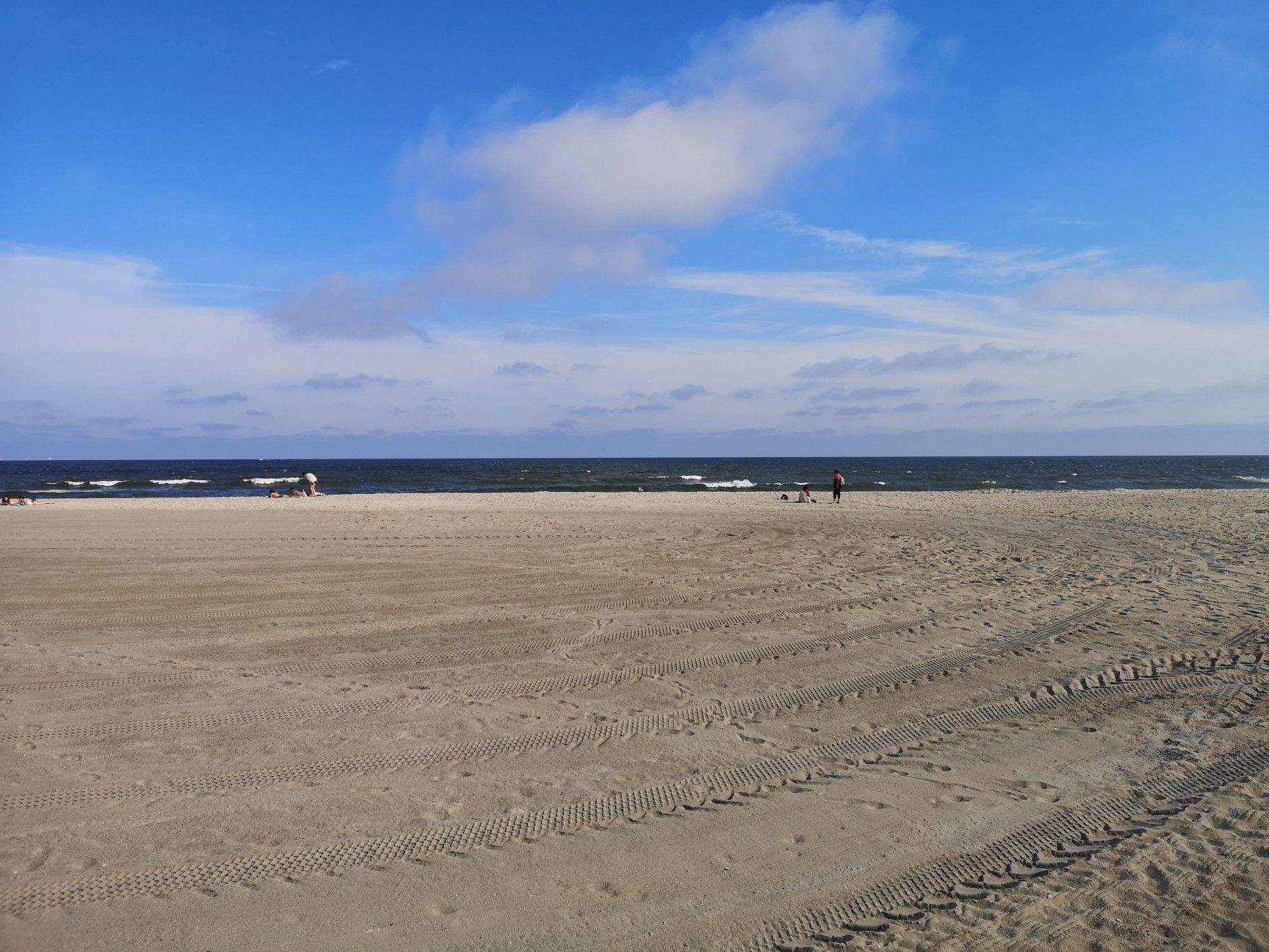 Sandy beach with tire tracks, ocean, and a clear blue sky. - Rockaway Beach – Jacob Riis Park Beach loop from Rockaway Park–Beach 116th Street