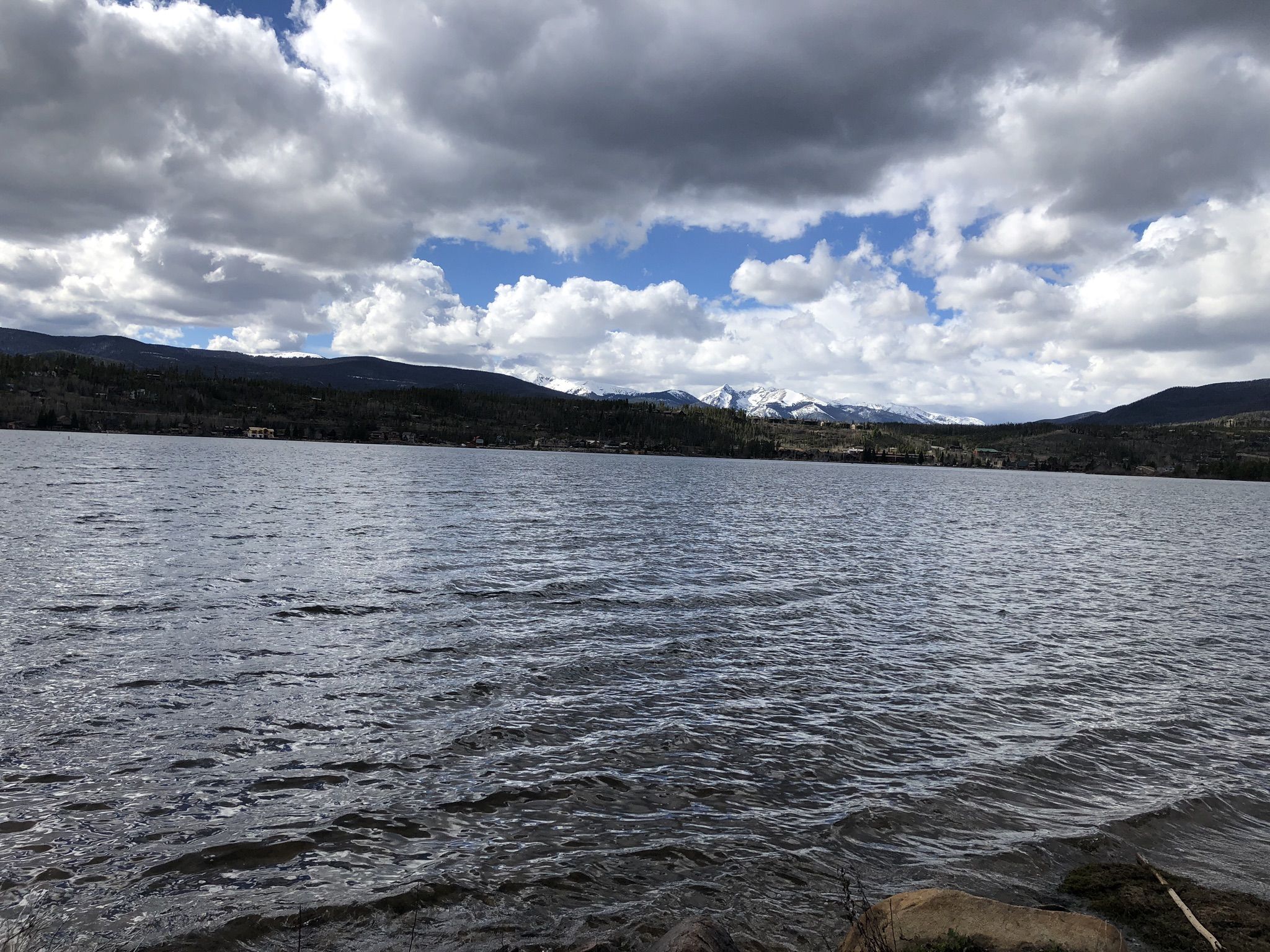 A wide lake with mountains and a cloudy sky in the background. - Shadow Mountain Lookout Trail